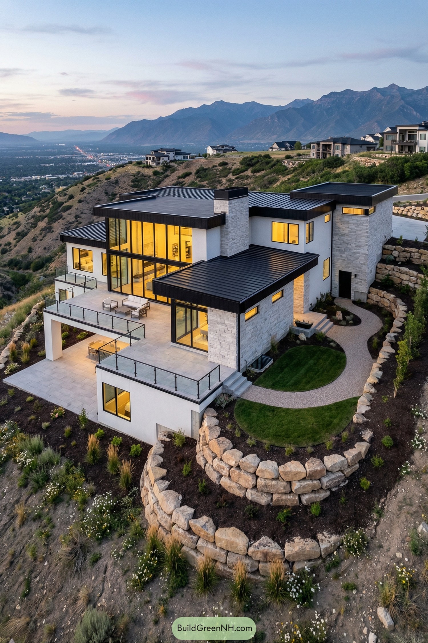 Modern hillside home with tiered stone terraces and wide glass balconies overlooking a mountain valley