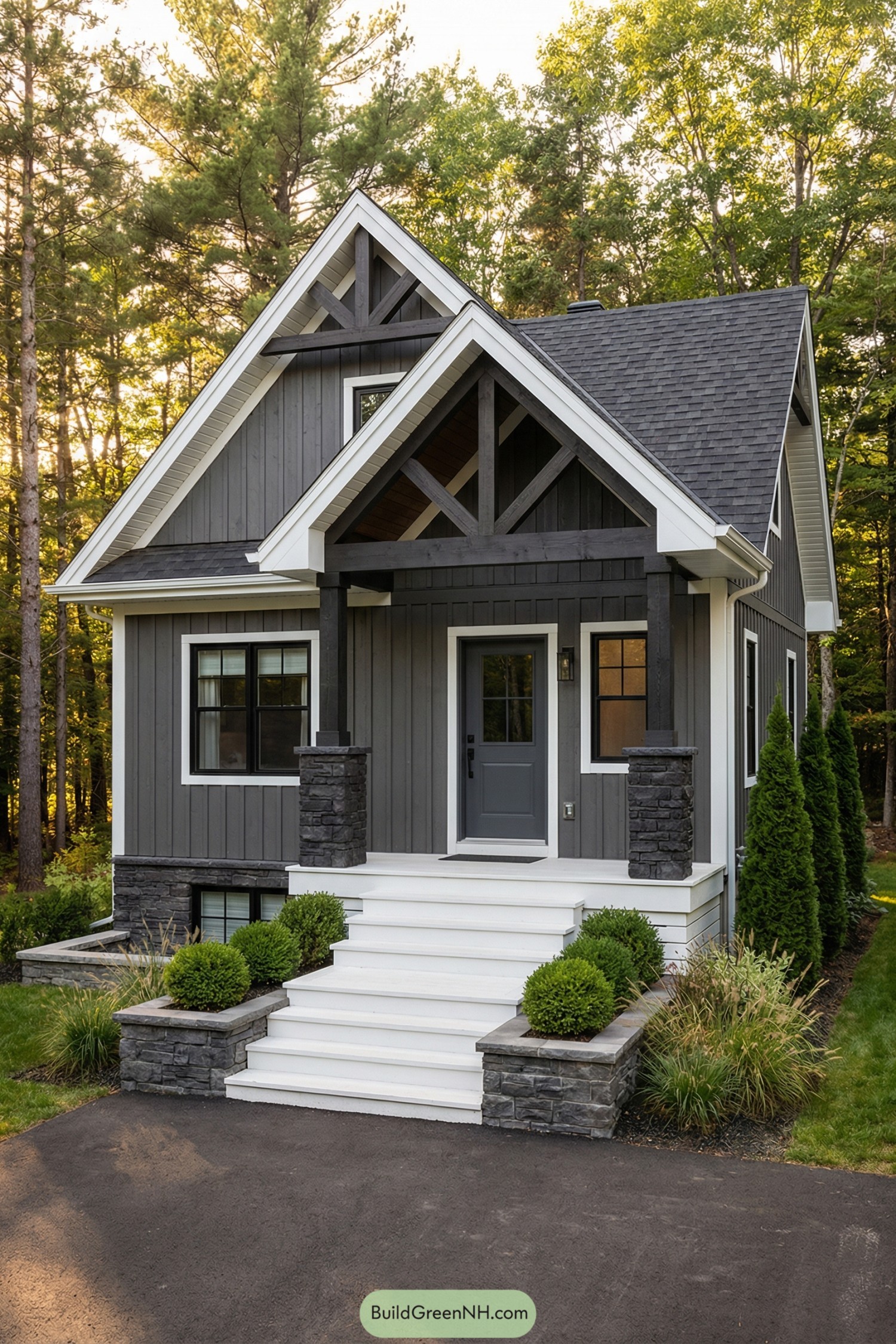 Small gray gabled cabin with stone-accented porch and white steps set in a wooded clearing