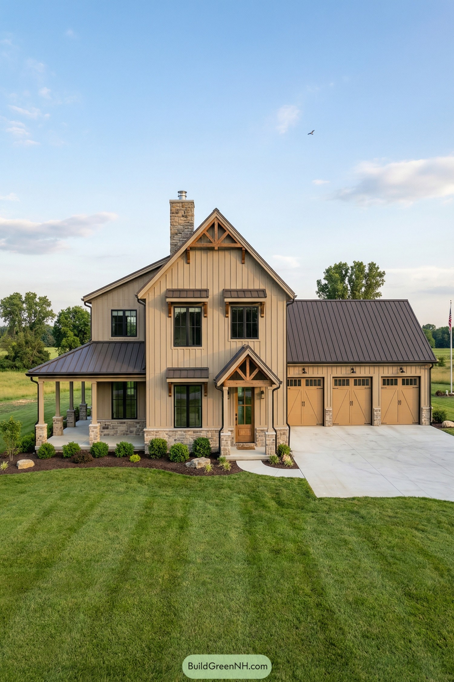 Two-story tan barndominium with metal roof, stone accents, and attached three-car garage set in a wide green lawn