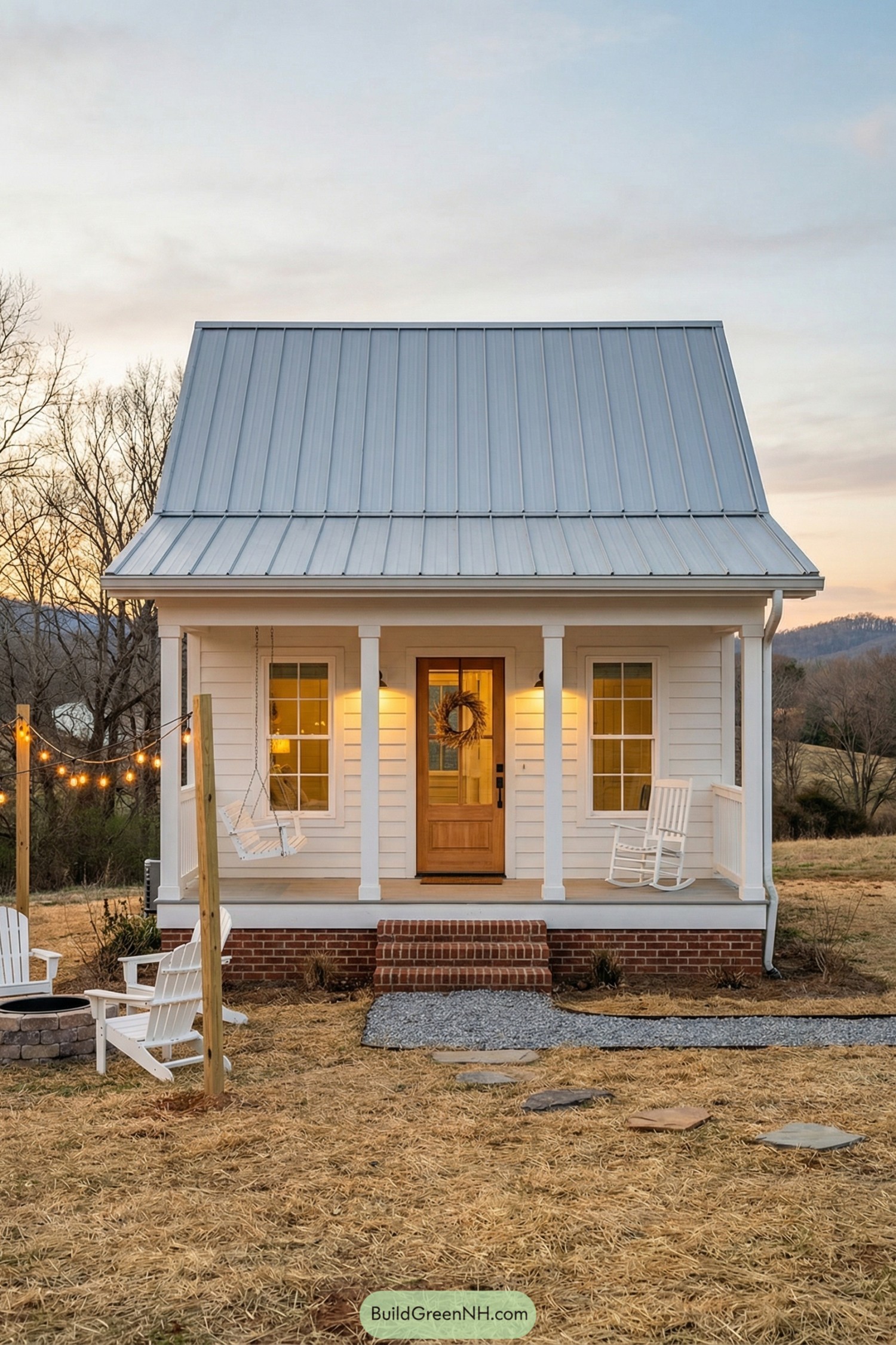 Small white cottage with metal roof and front porch at dusk
