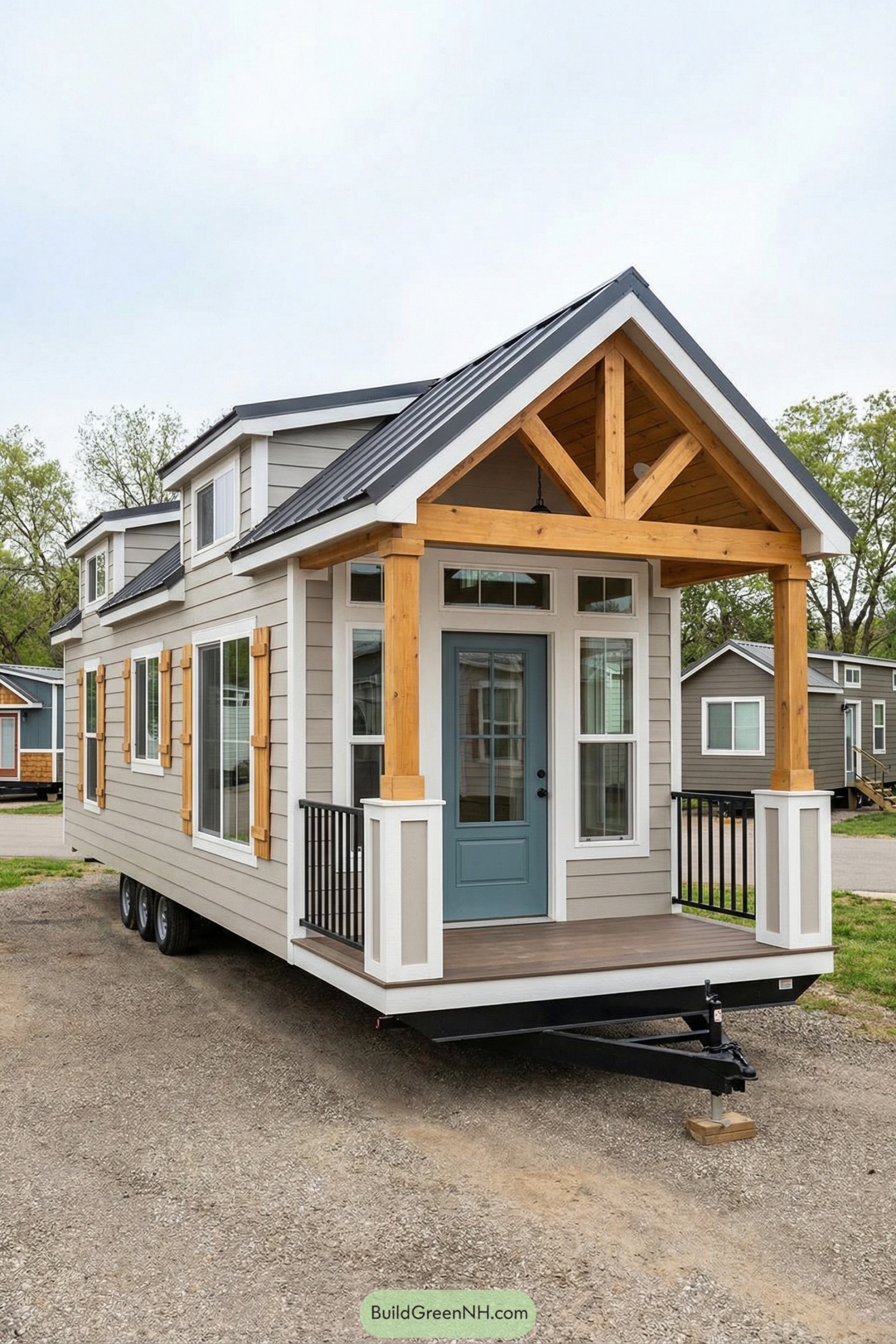 Tiny house on wheels with blue front door, timber porch, and dormer windows