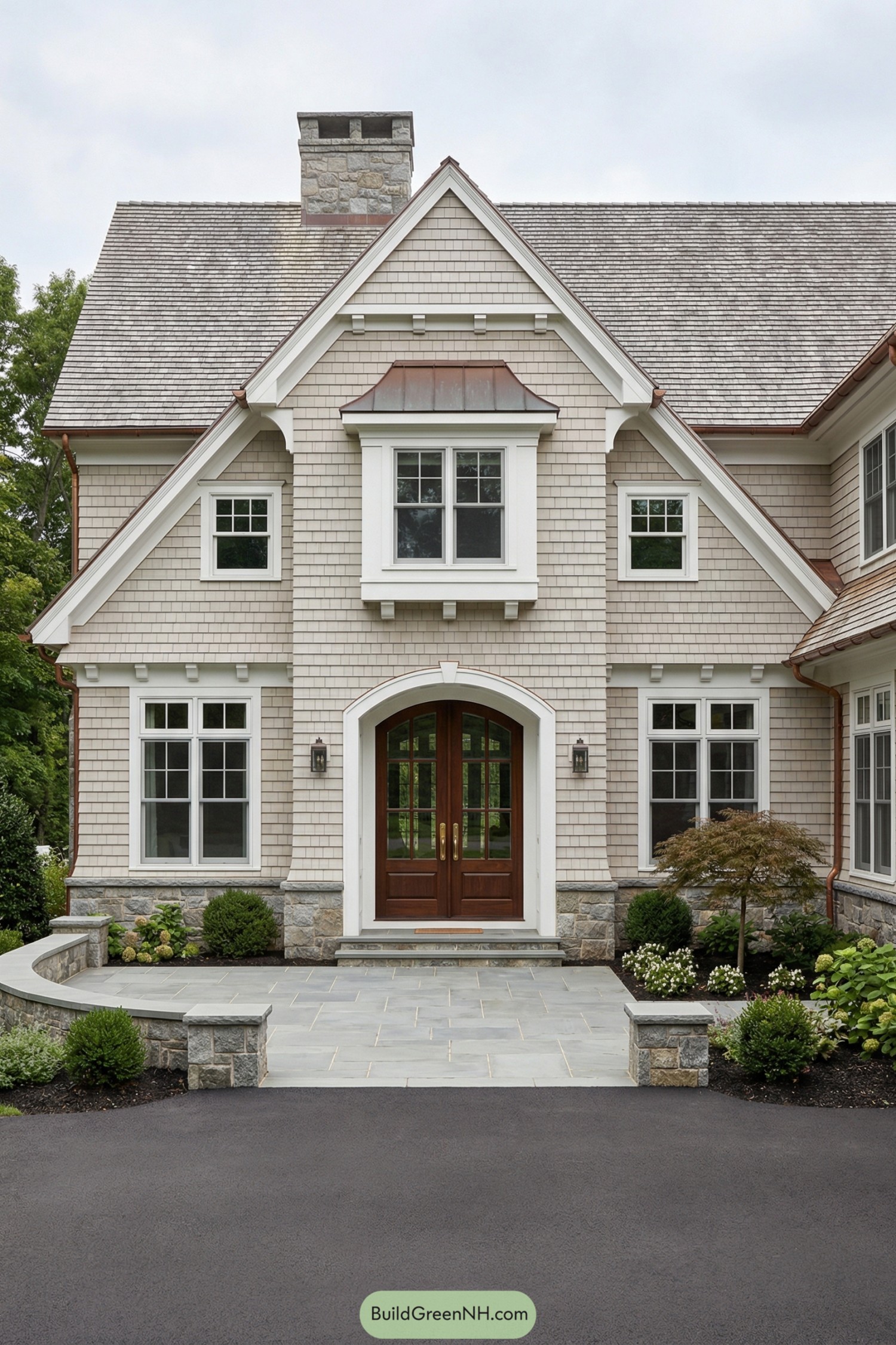 Light gray shingle house with gables and arched wooden entry door