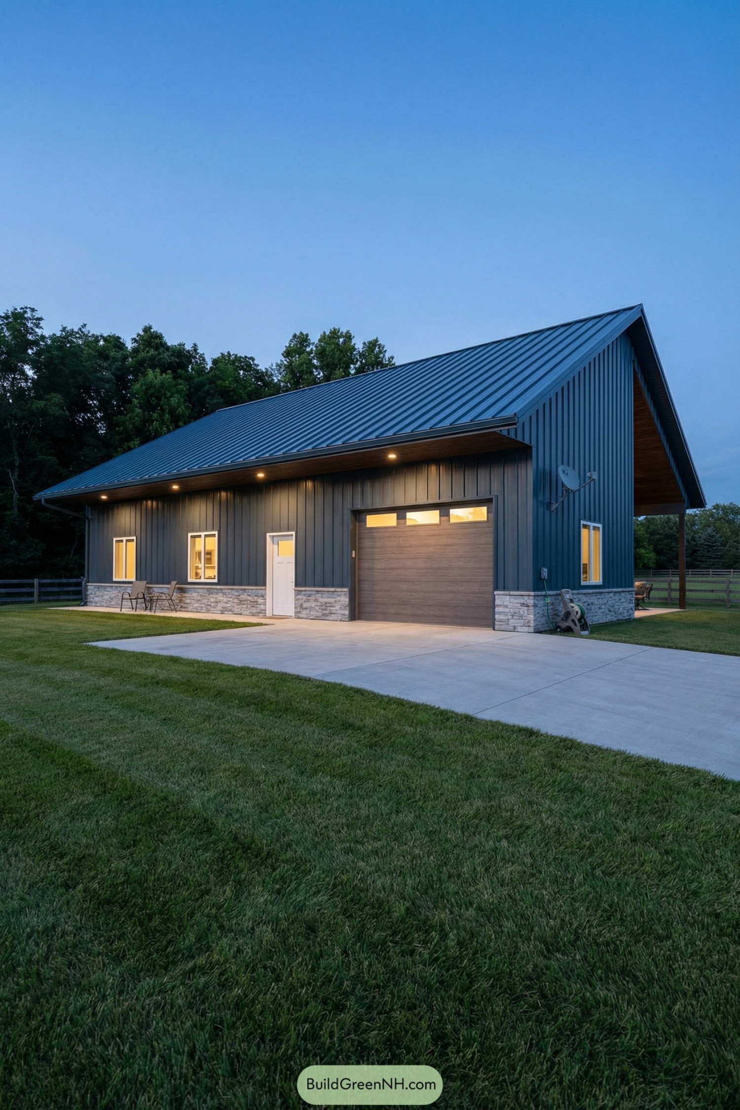 Modern metal-sided garage with stone base, single bay door, and deep overhang lighting at dusk