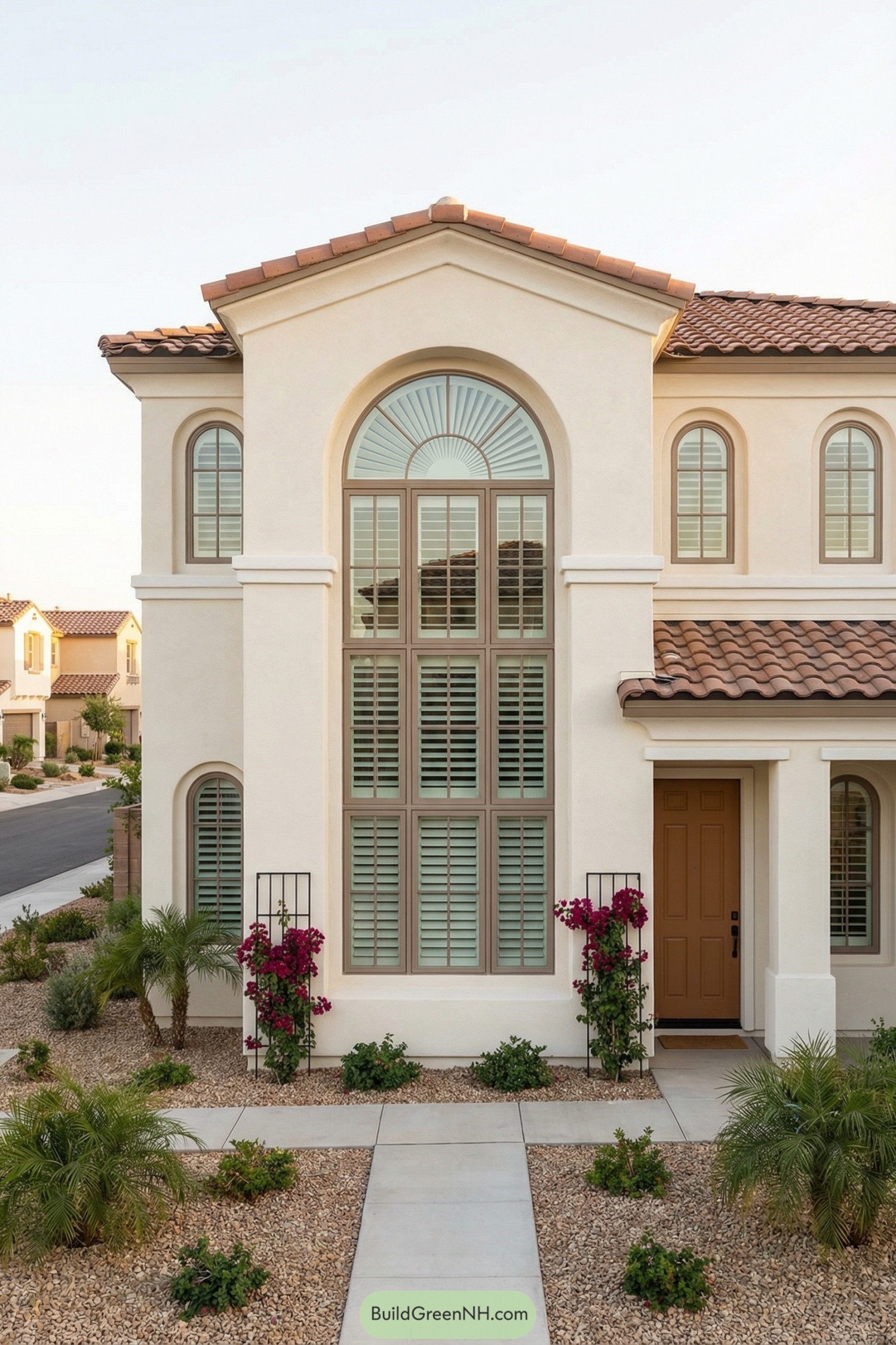 Cream stucco house with tall sunburst arched window and terracotta tile roof