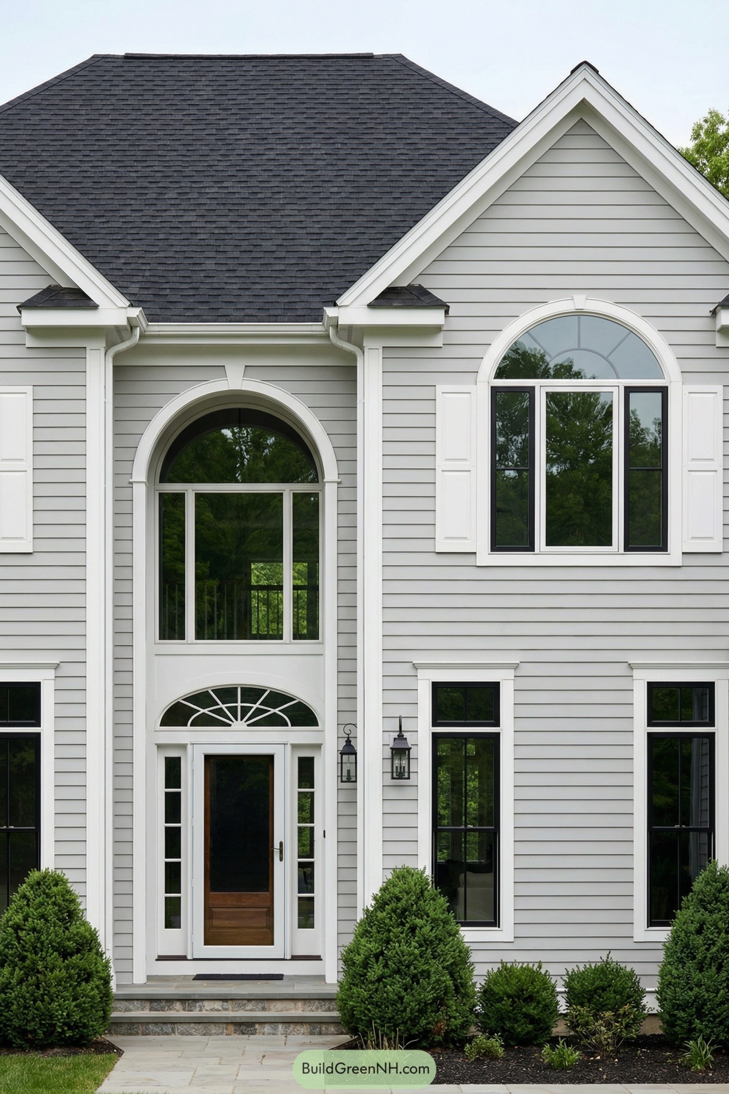 Gray two-story house with symmetrical arched windows and white trim around a central entry