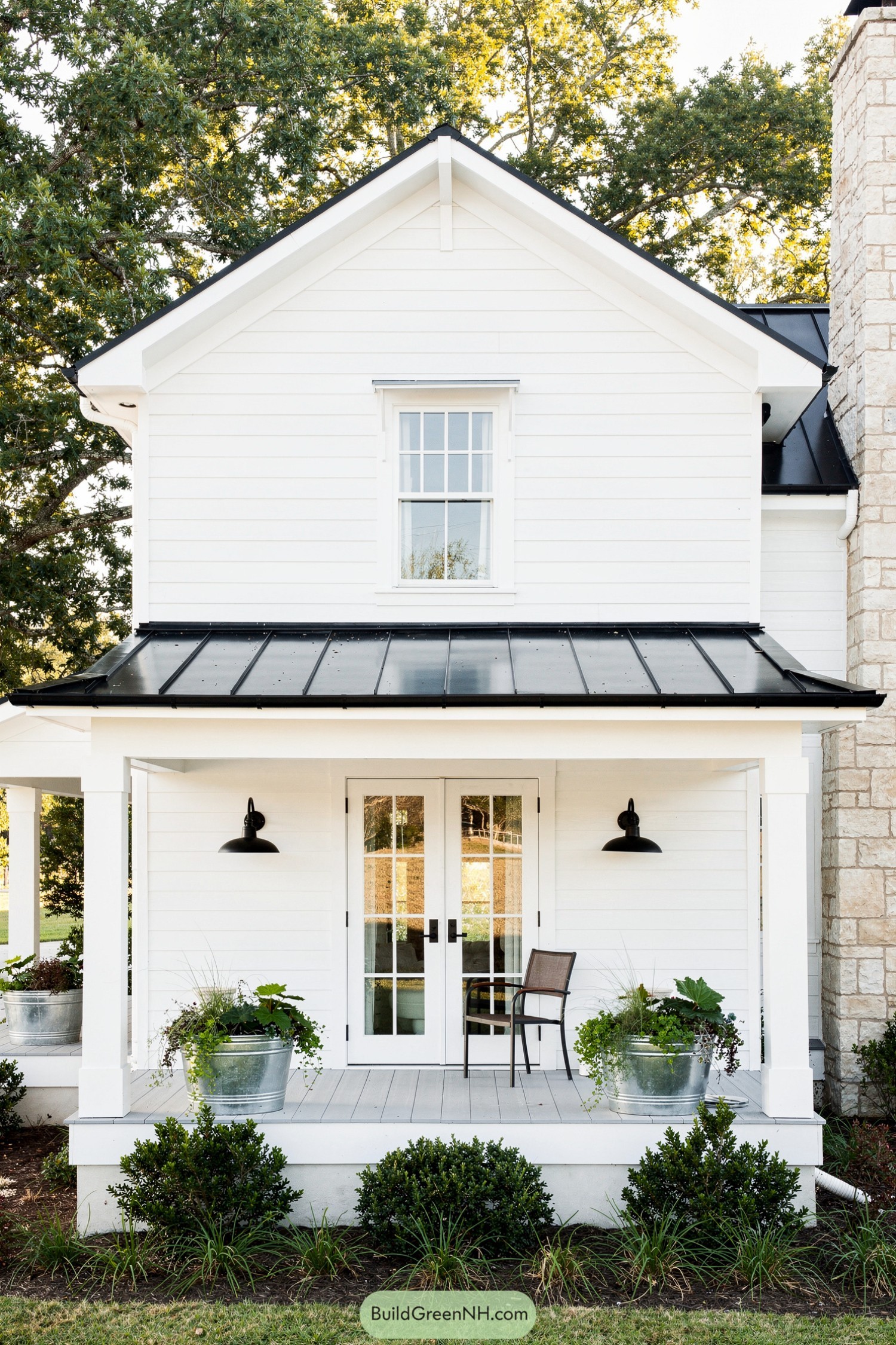 White shiplap house front with black metal porch roof and French doors