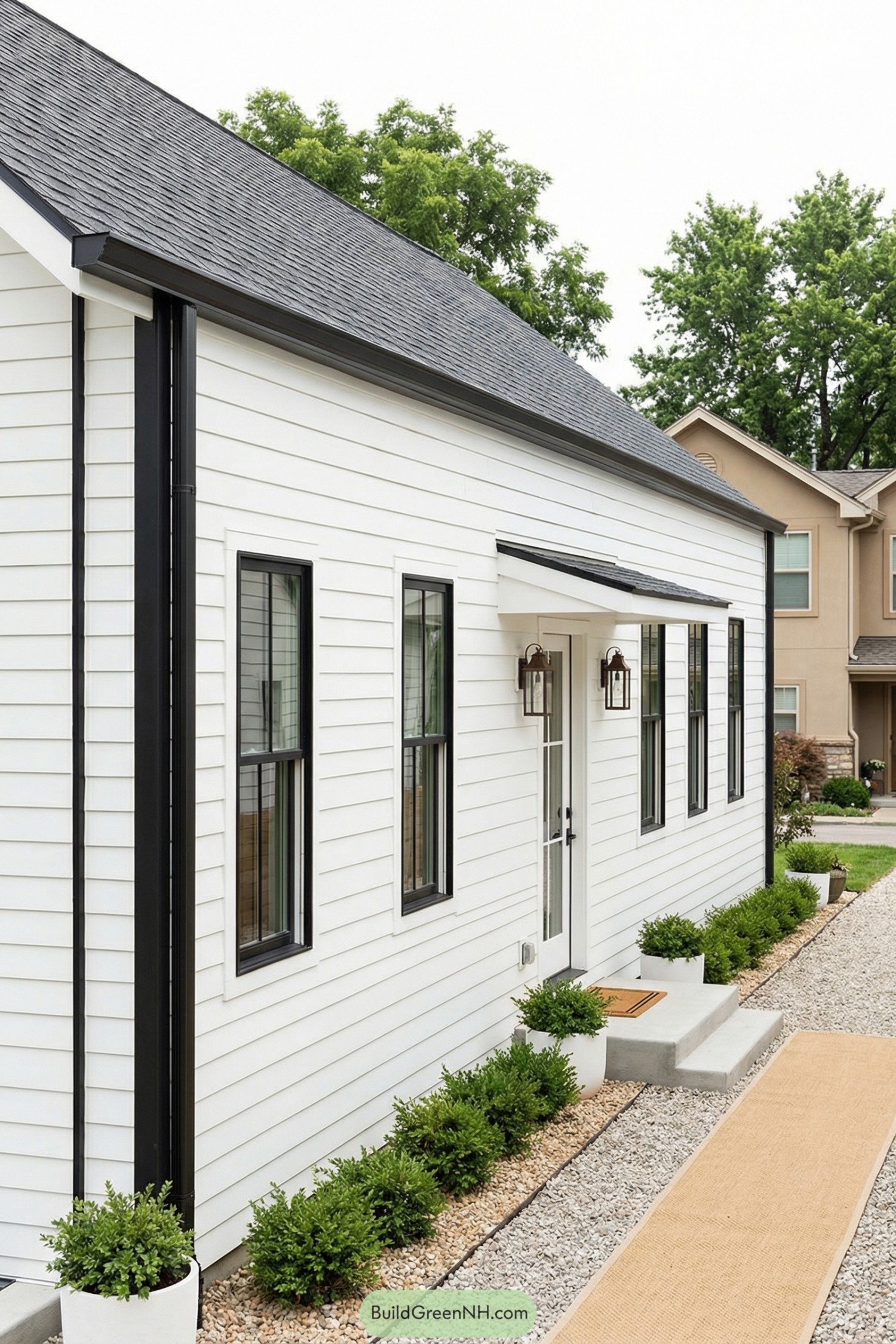 White shiplap house with black trim and gravel path