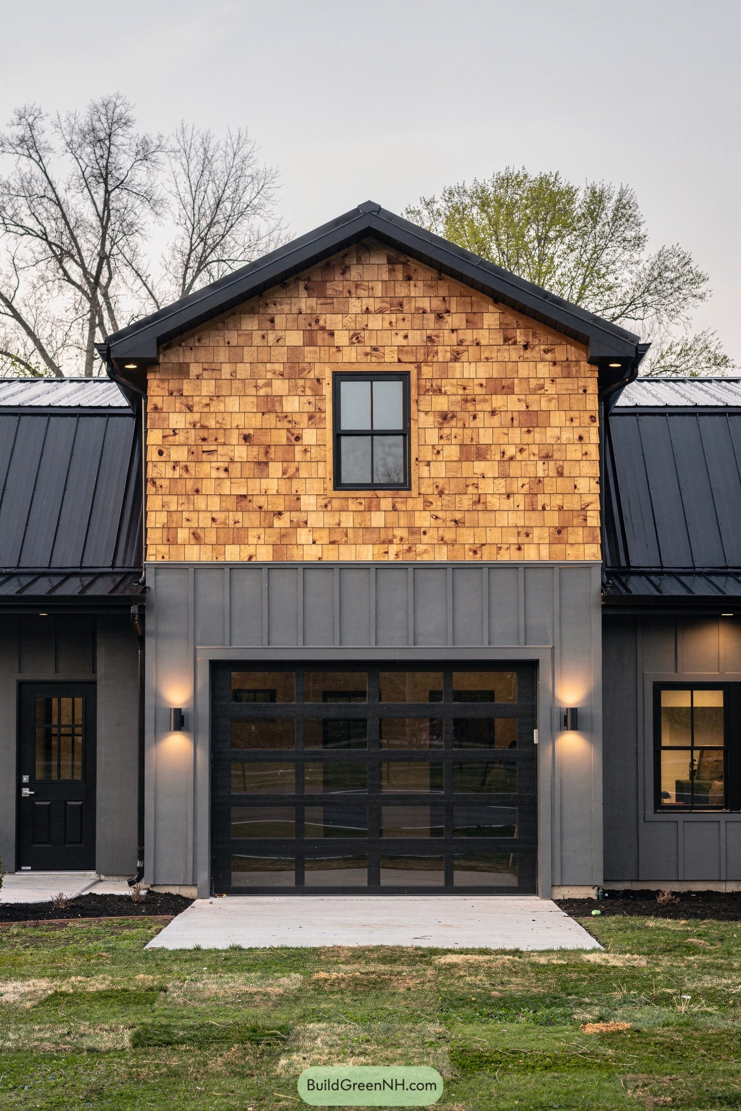 Front view of modern house with cedar shingle upper level and black metal roof