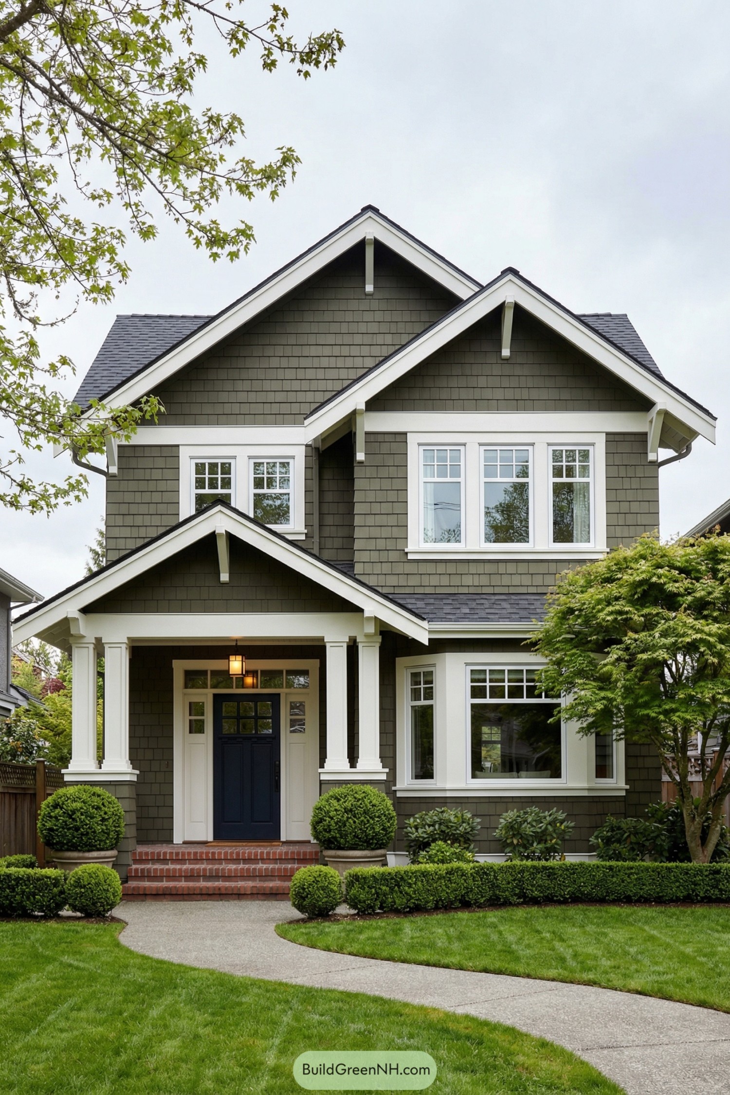 Two-story green Craftsman home with white trim and navy front door