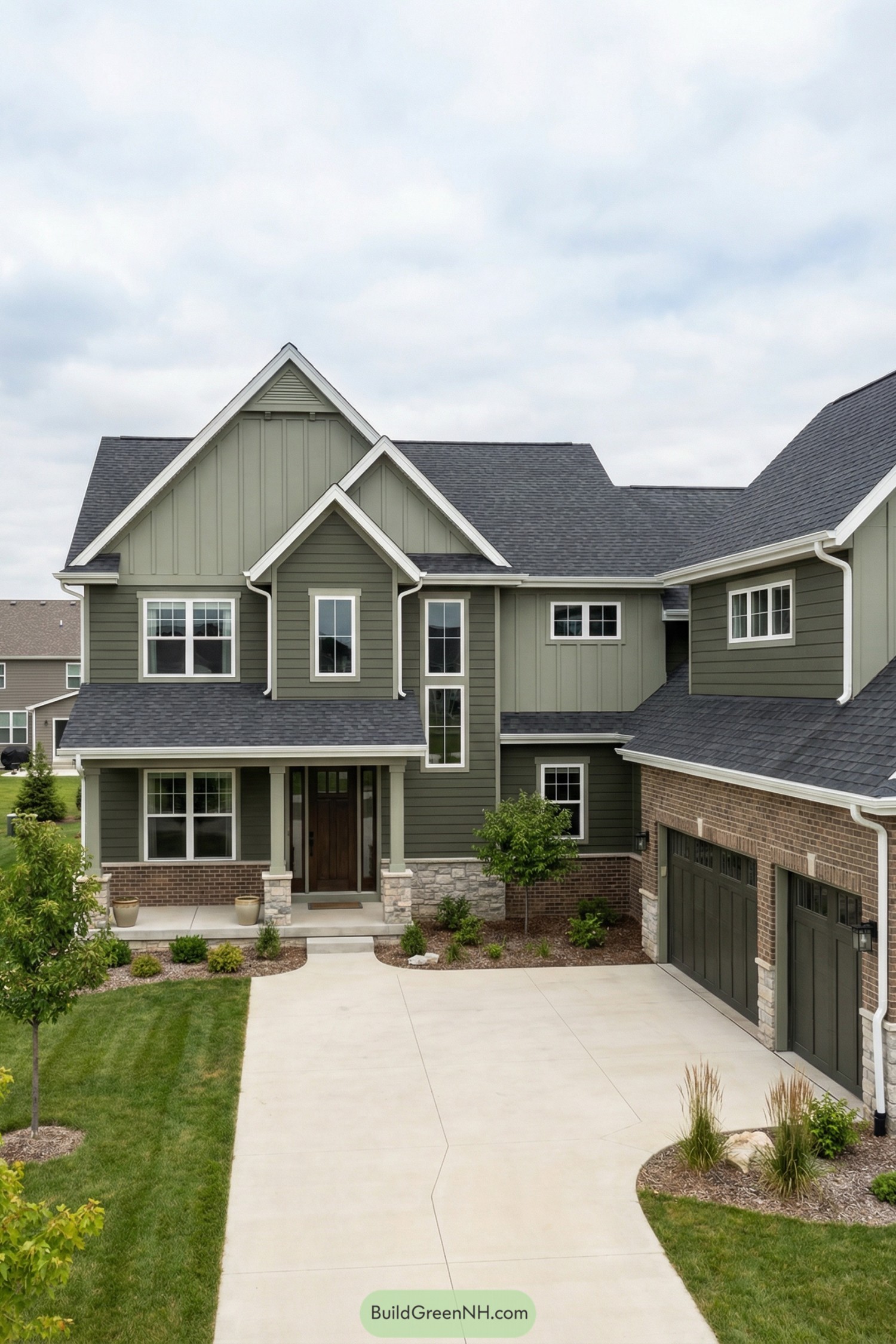 Green gabled two-story home with brick accents and three-car garage off a wide driveway