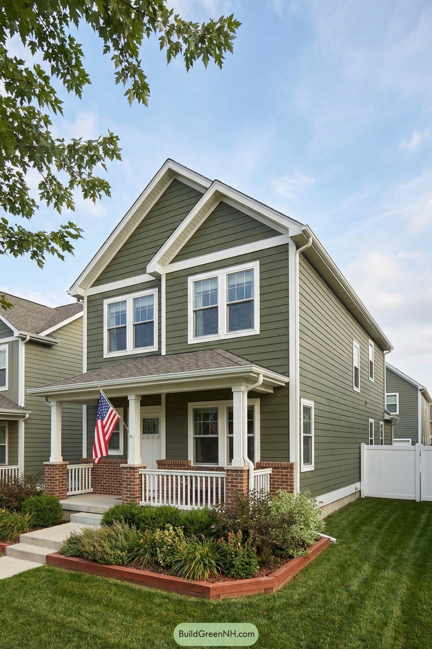 Two-story green-sided house with white trim and brick porch columns