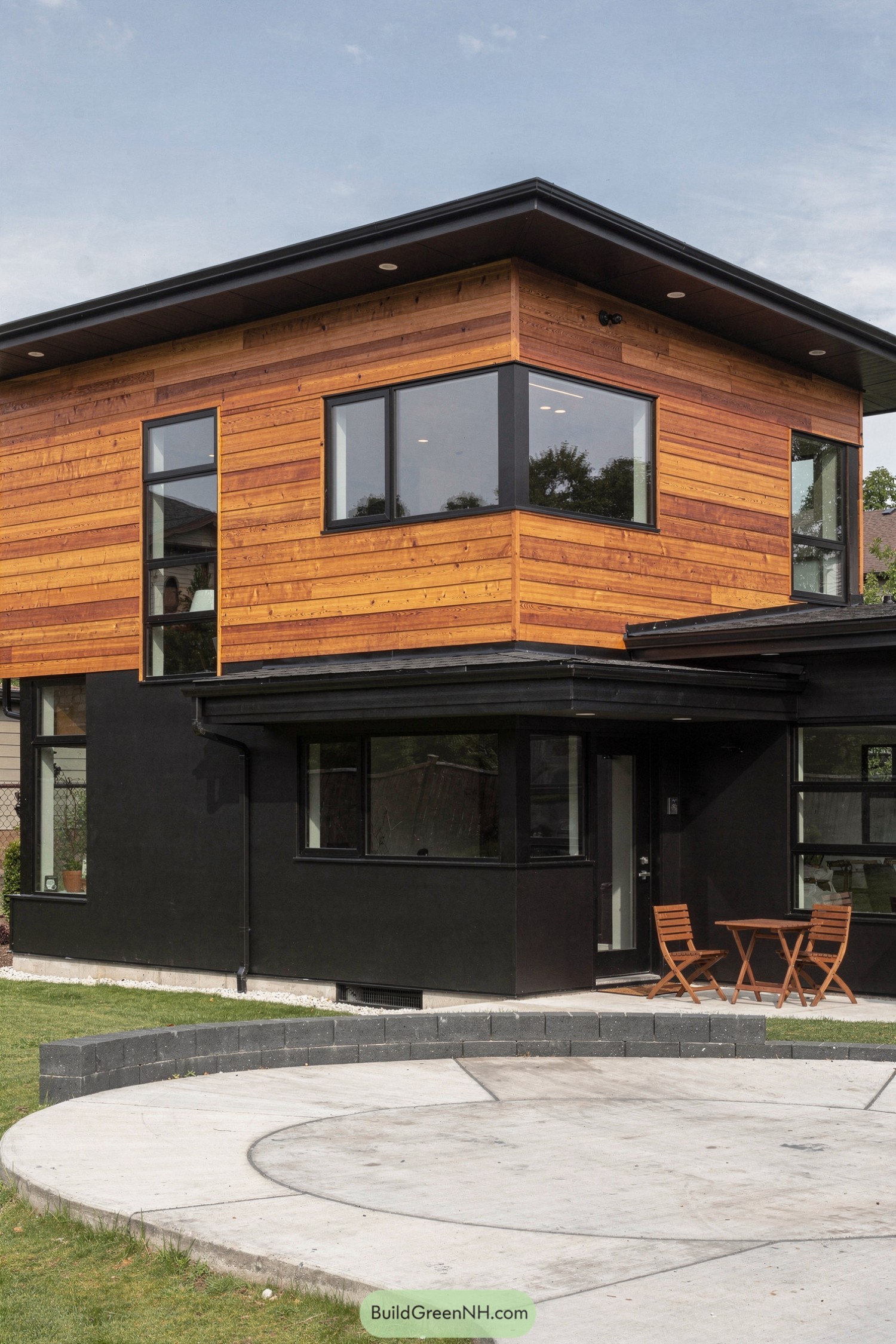 Two-story modern house with warm cedar upper siding over black lower walls and large windows