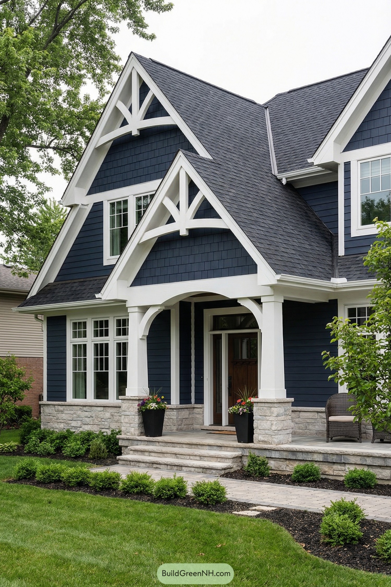 Navy blue craftsman home with white-trimmed porch gable and stone base