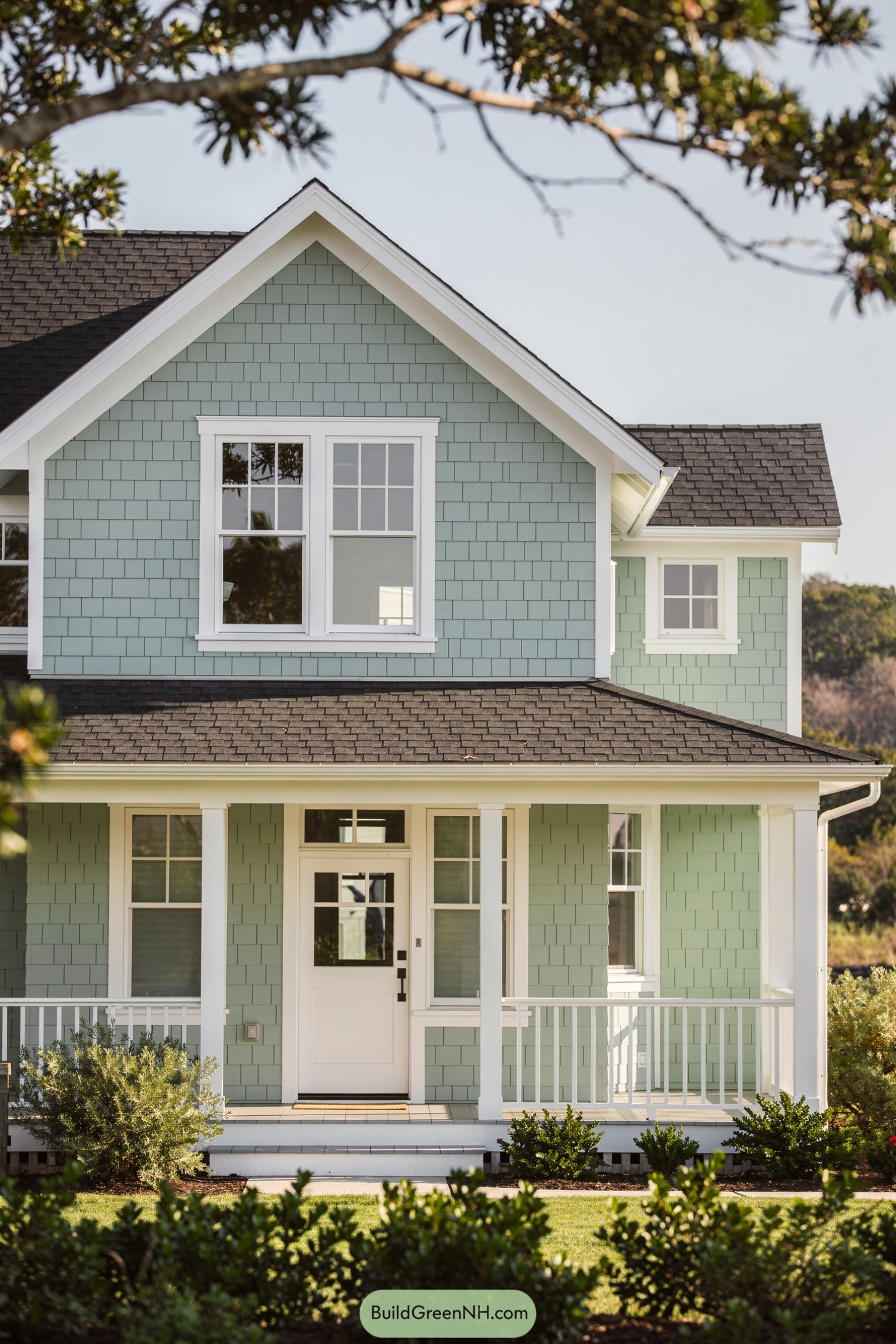 Light green shingle cottage with white trim and a covered front porch