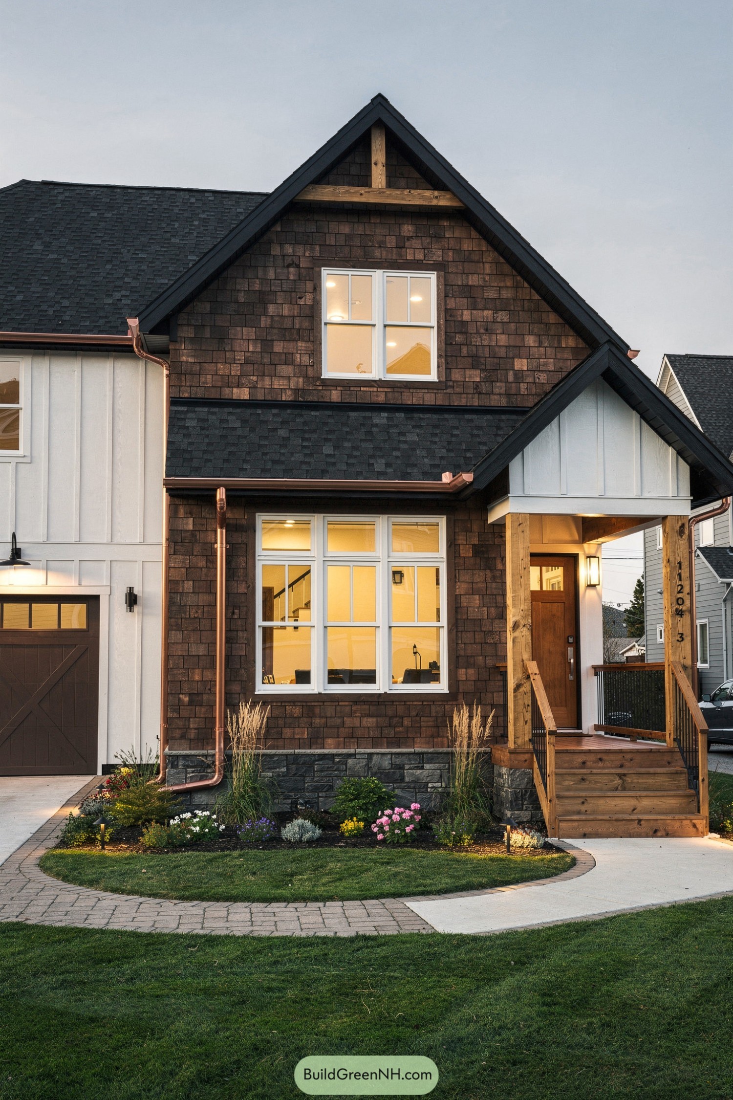 Cozy two-story shingle house with copper accents and a small front porch at dusk