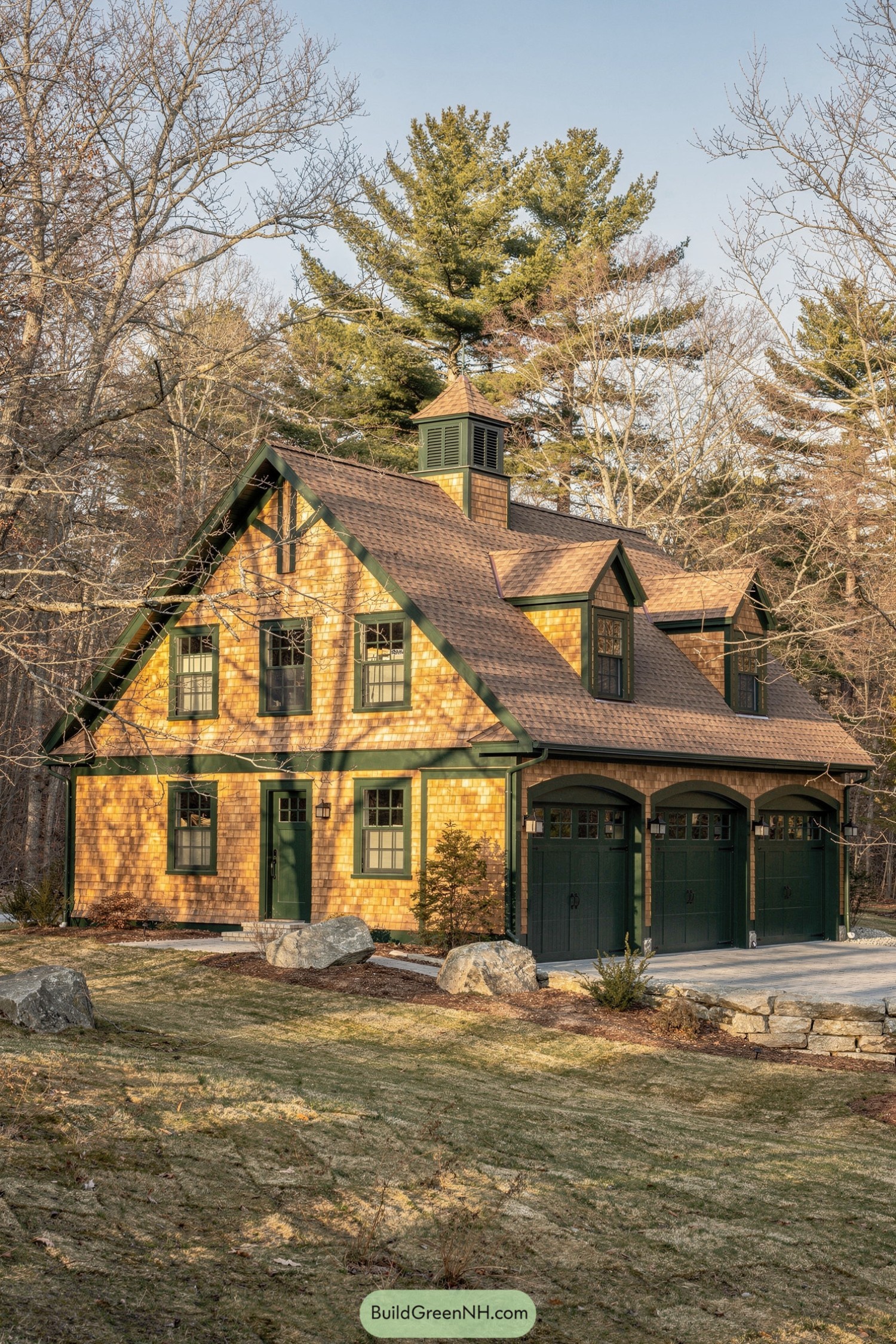 Two-story shingle-sided carriage house with green trim and three arched garage doors