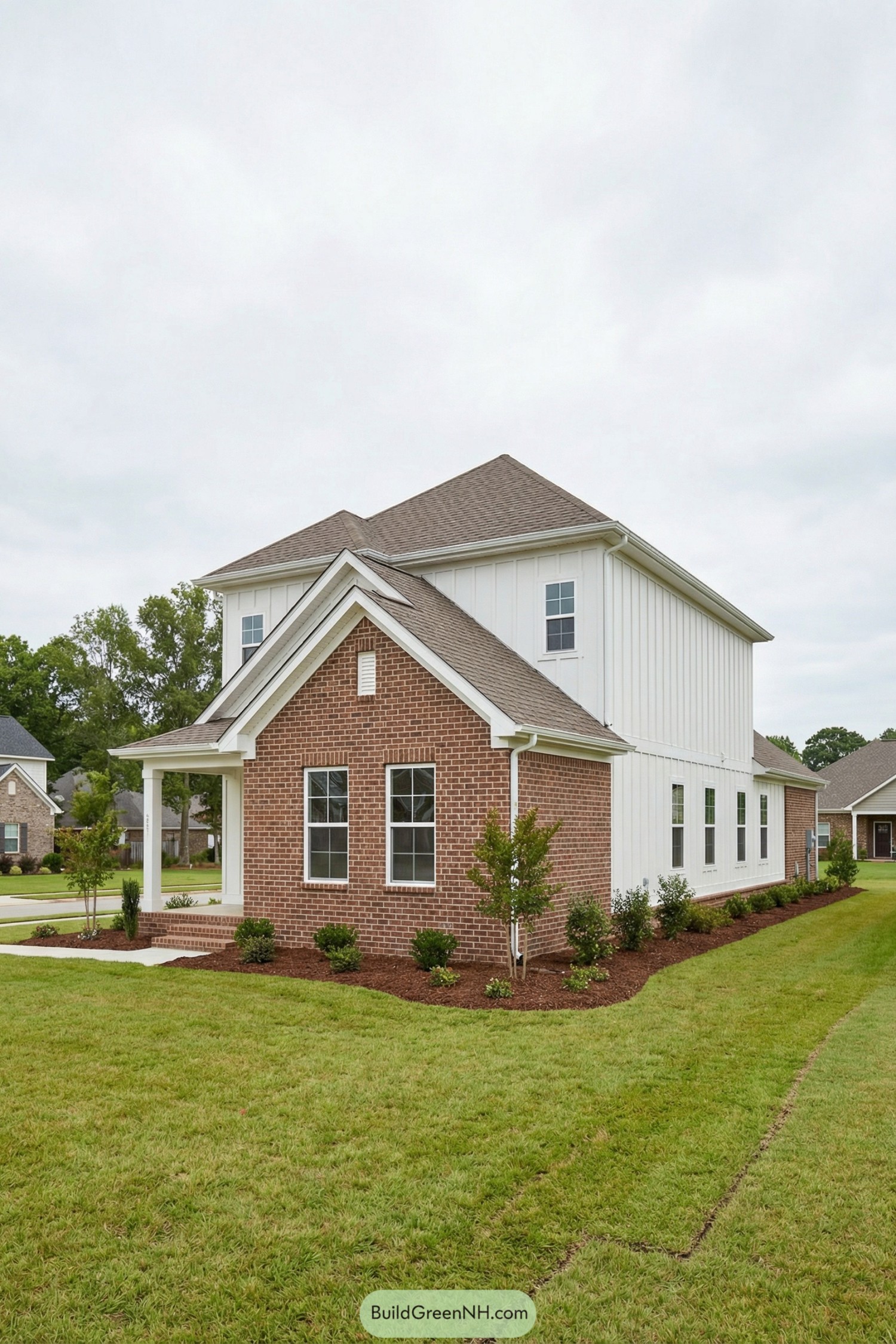 Two story home with red brick front and white vertical siding along the sides and rear