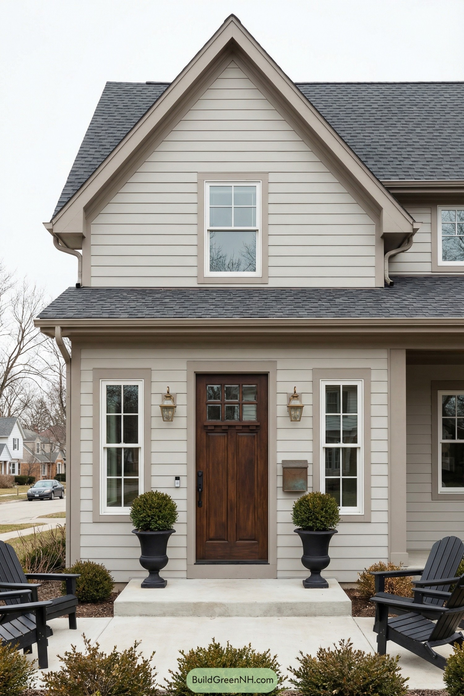 Front entry of taupe house with dark wooden door and two planters