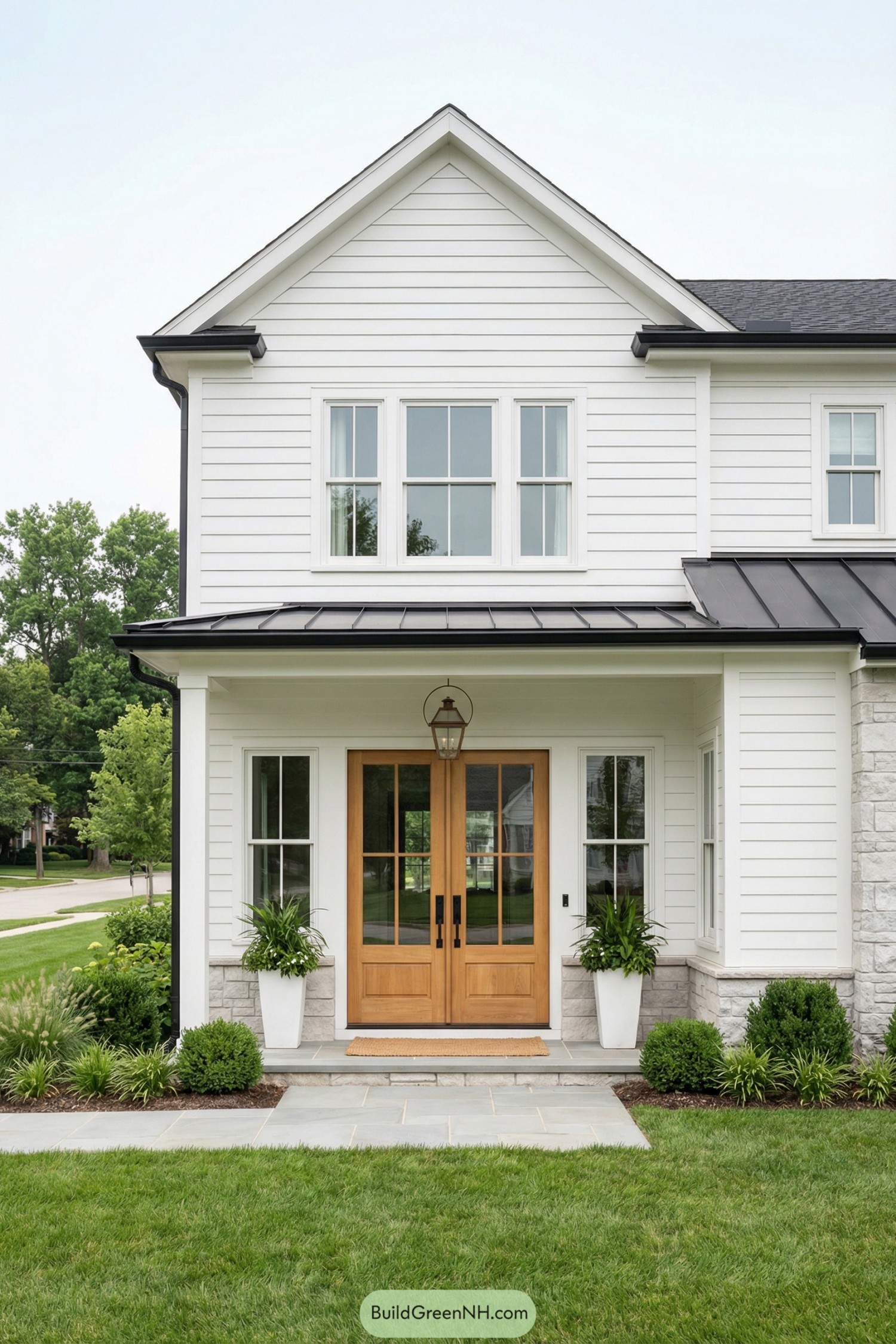 White farmhouse entry with natural wood double doors and potted greenery