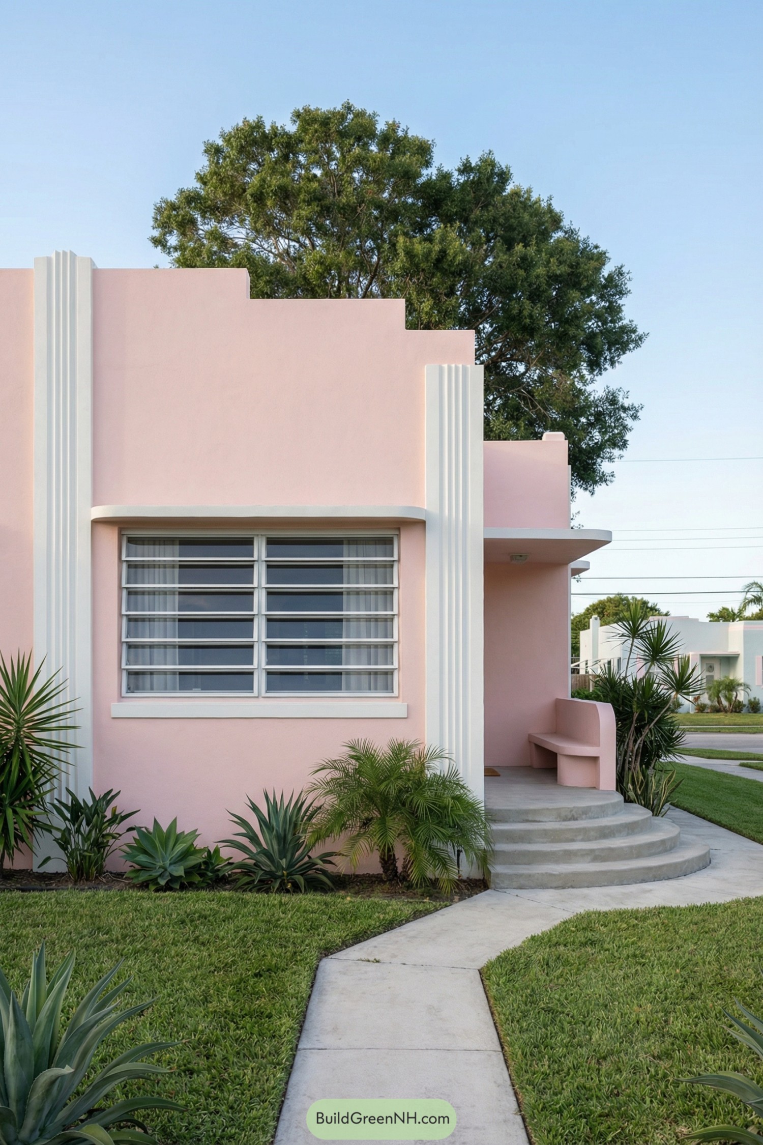 Soft pink art deco house with curved entry steps and tropical landscaping