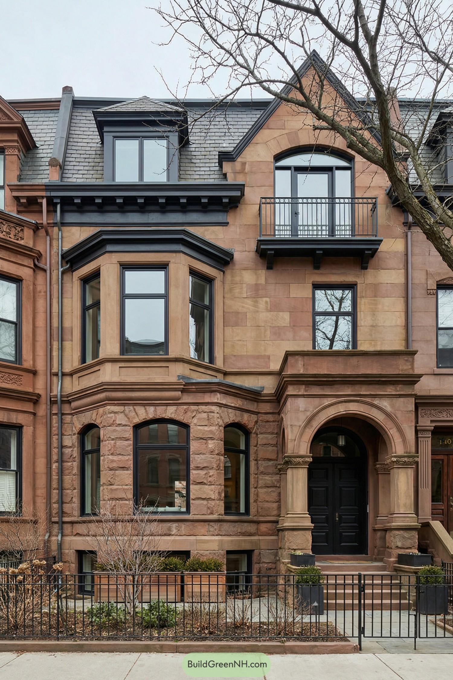 Restored brownstone townhouse facade with arched entry, bay windows, and dark framed openings
