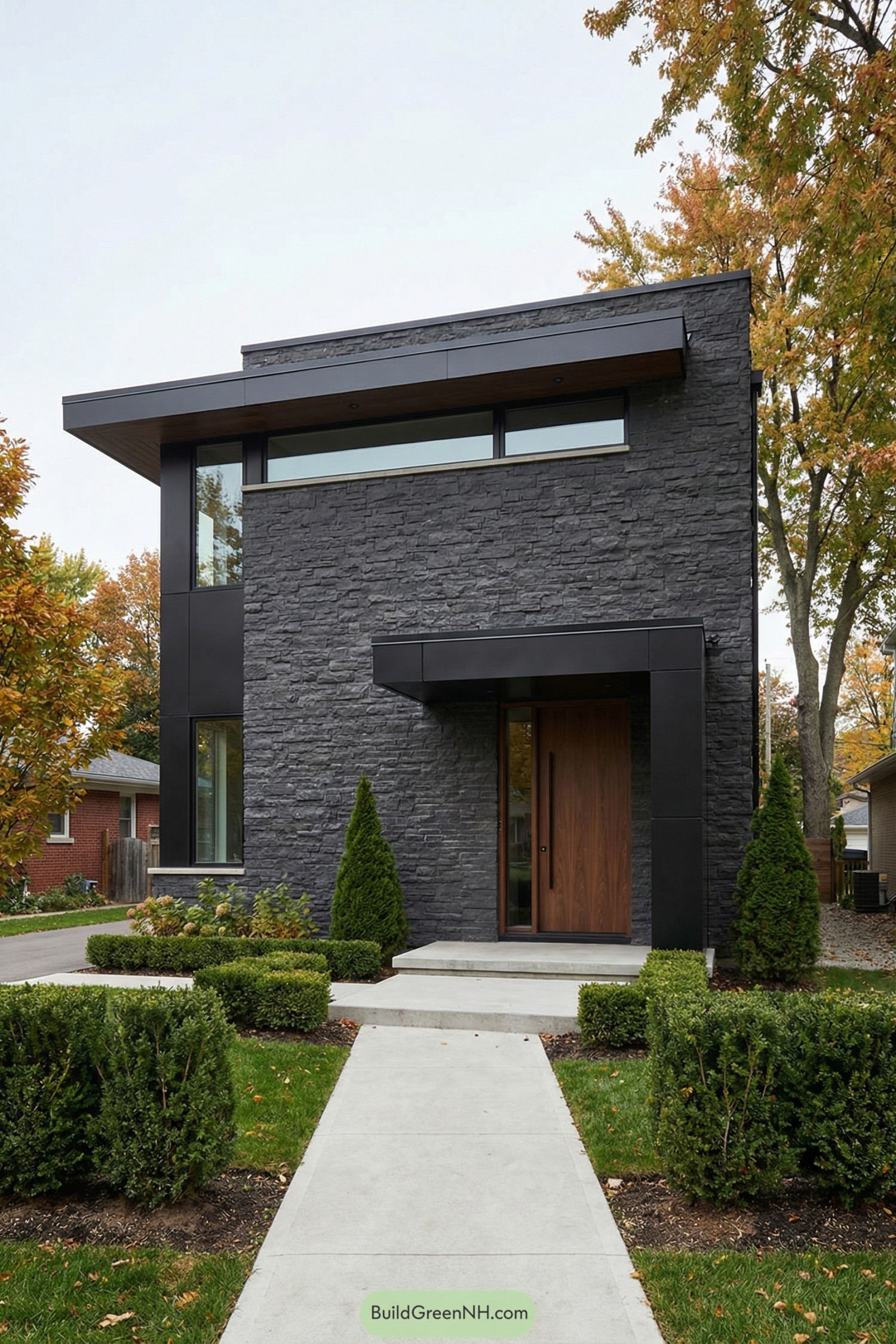 Modern dark stone house with flat roof and warm wood entry door