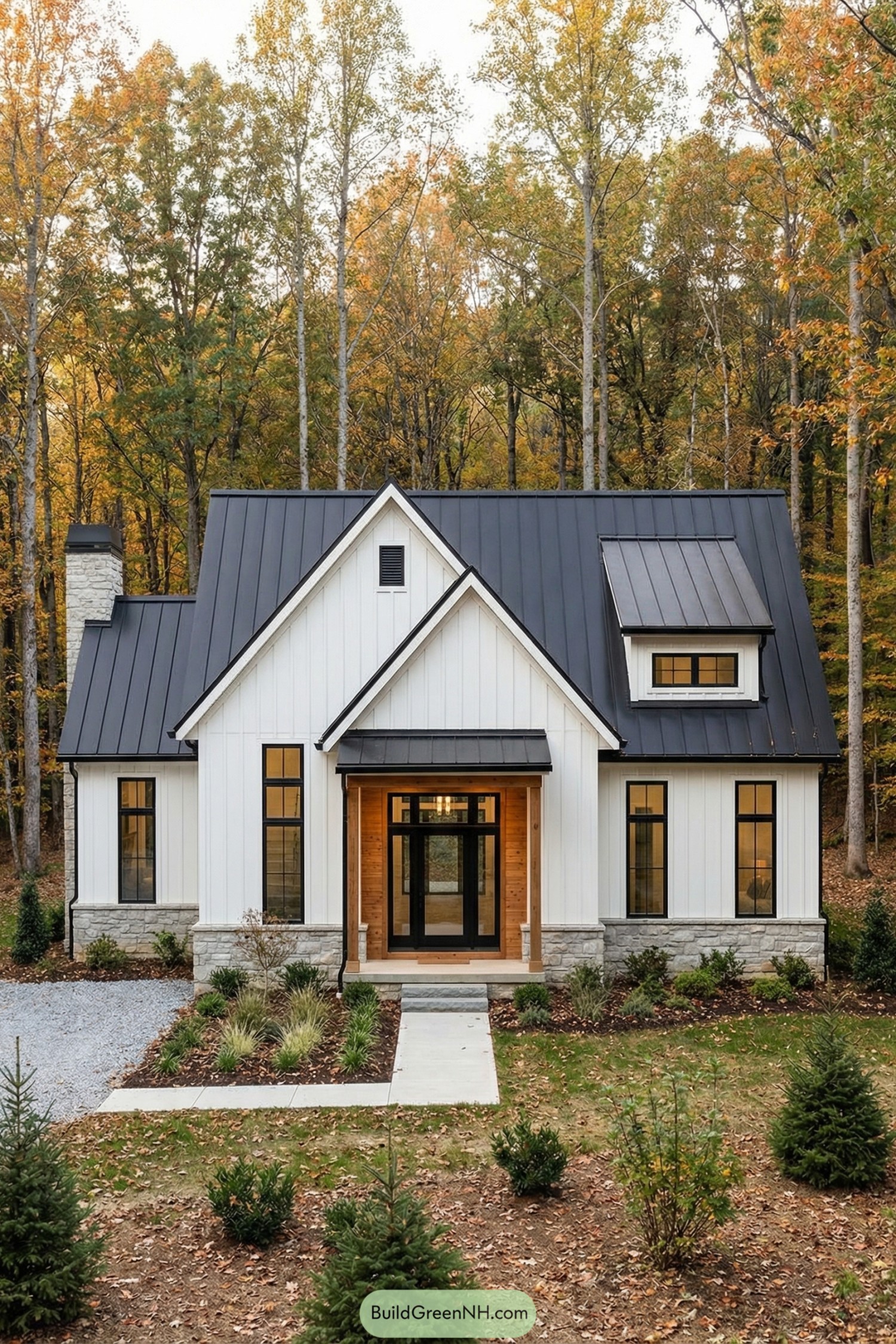White cottage with black metal roof set in autumn woods