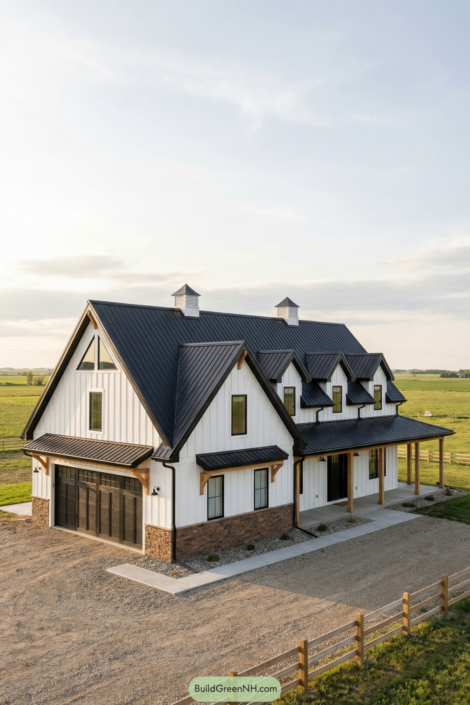 White farmhouse with black metal roof and stone base set in open countryside