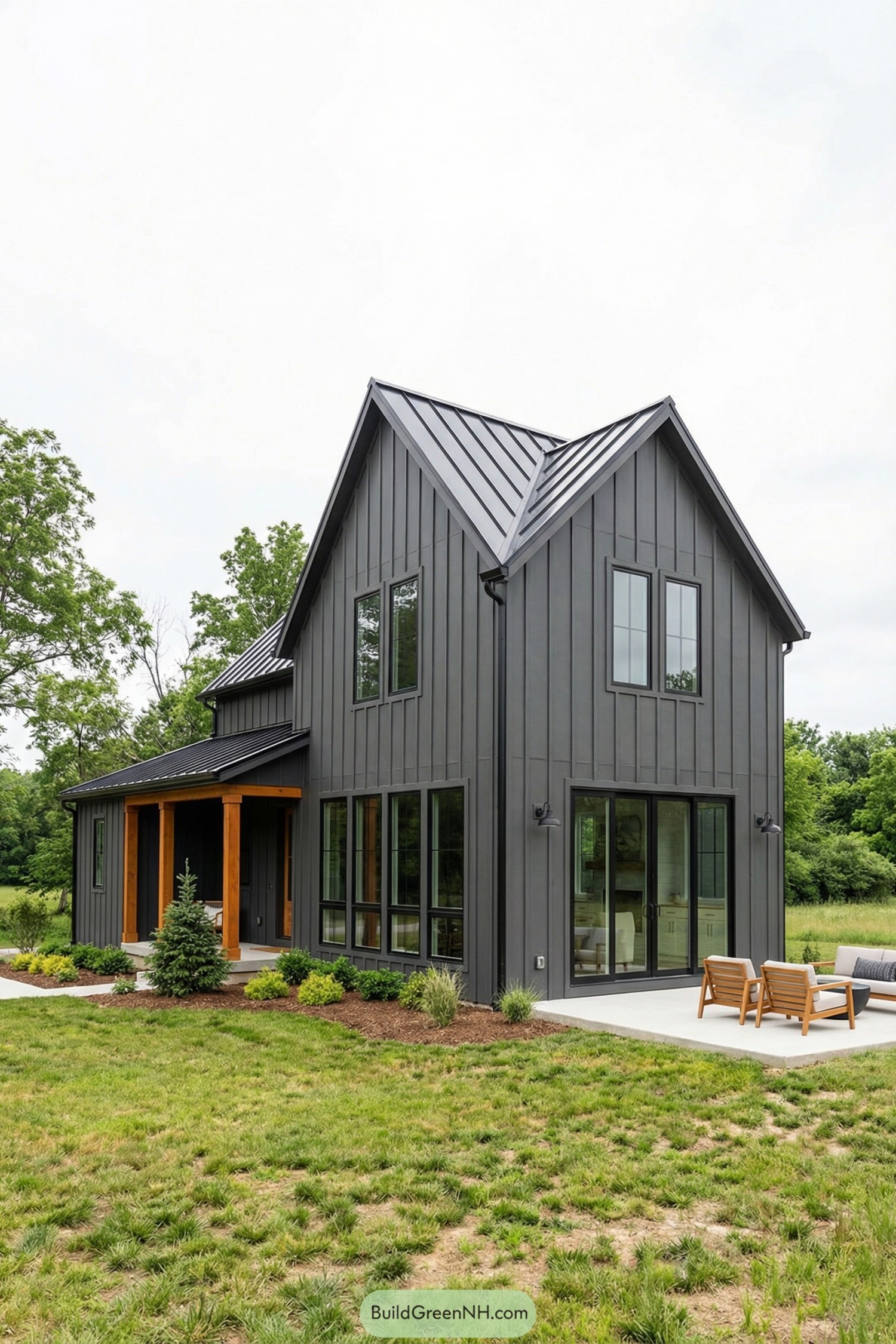 Modern dark gray farmhouse with black metal roof and large windows overlooking a simple patio