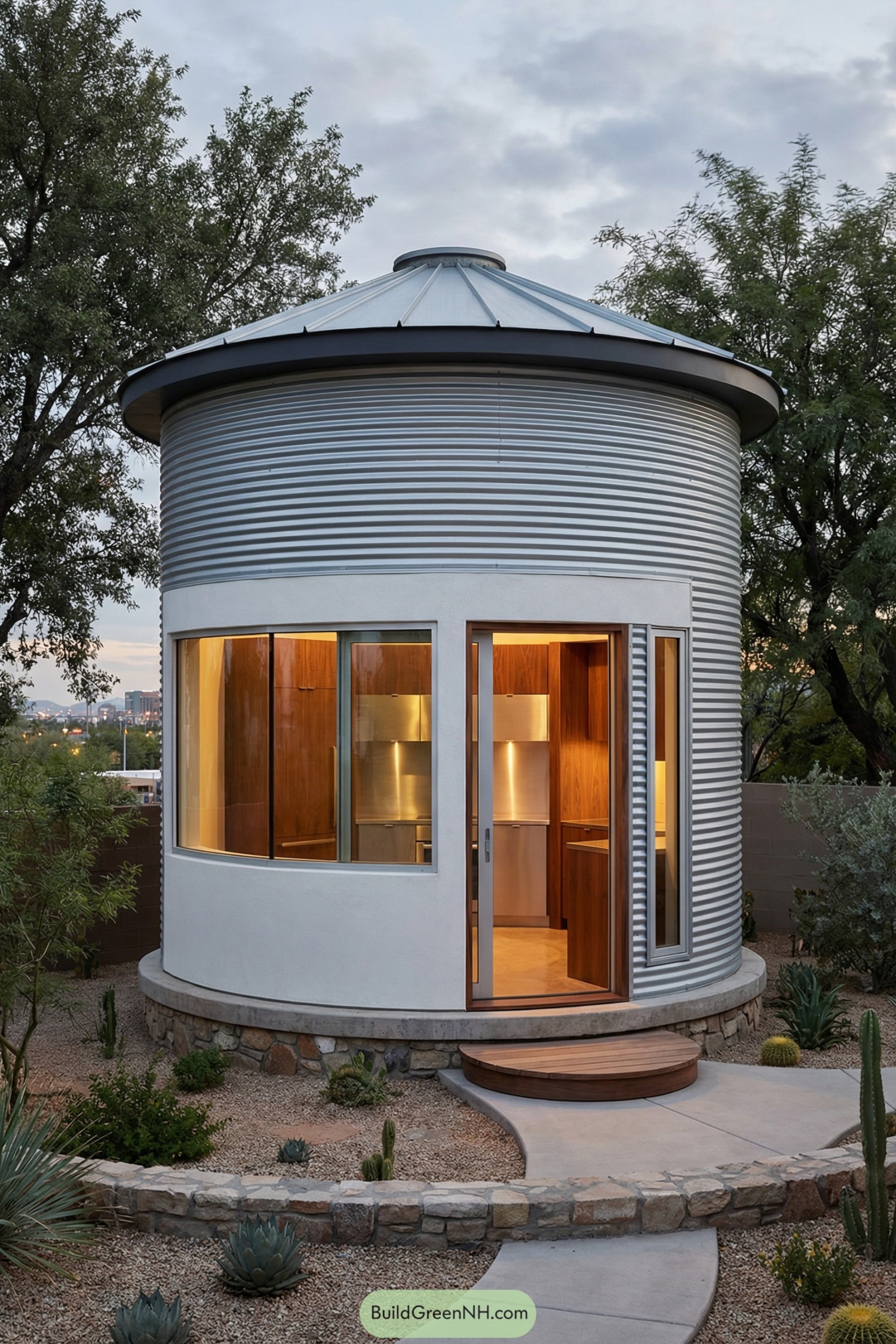 Small round metal-clad silo home with large windows and a warm wood-lined interior