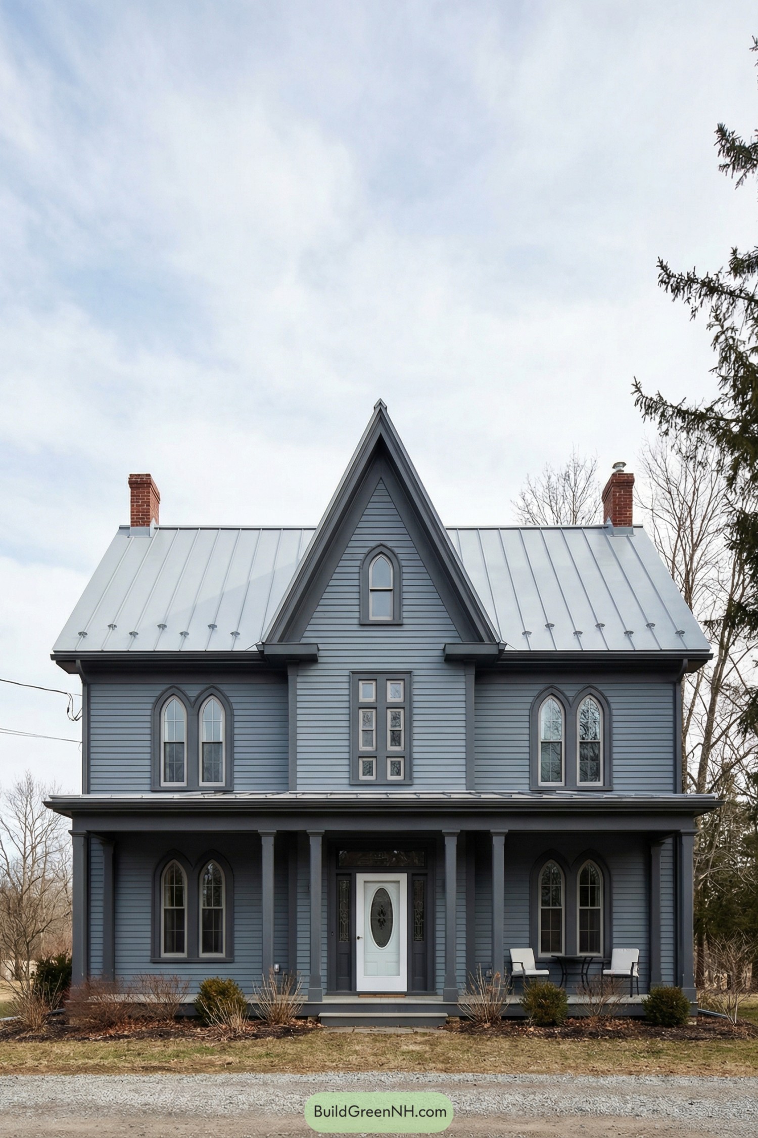 Gray-blue siding Gothic farmhouse with steep central gable, arched windows, and metal roof