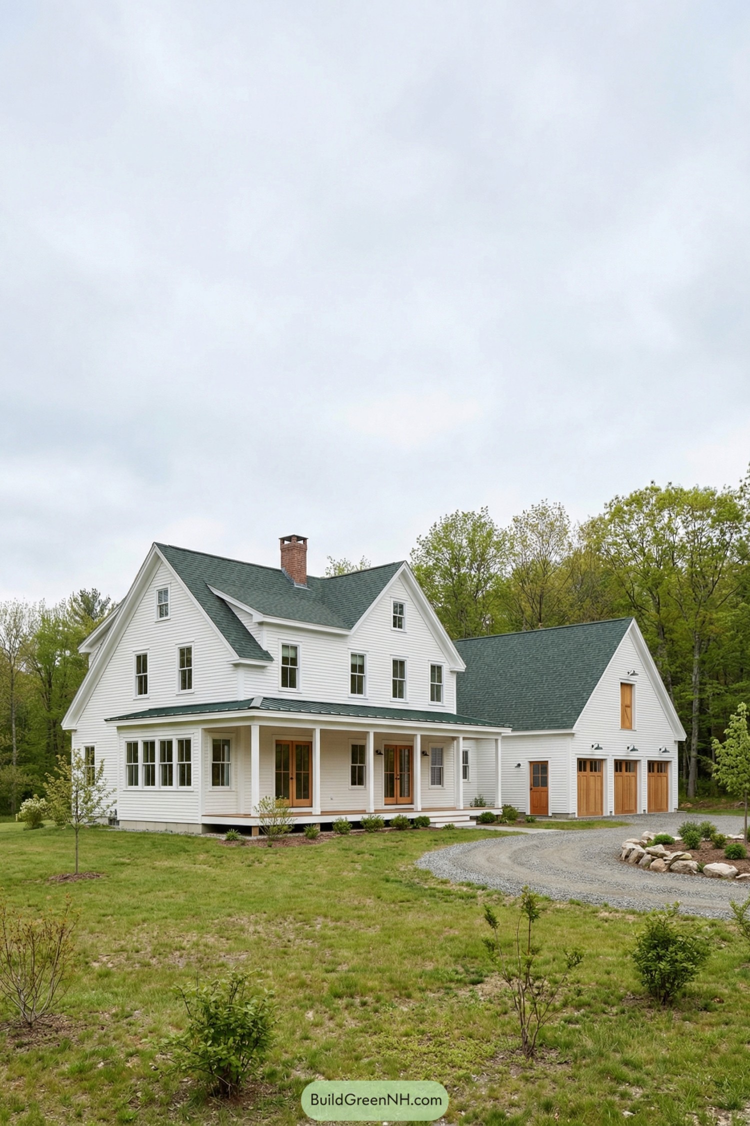 White farmhouse with deep porch and attached three-car garage set in a green rural landscape