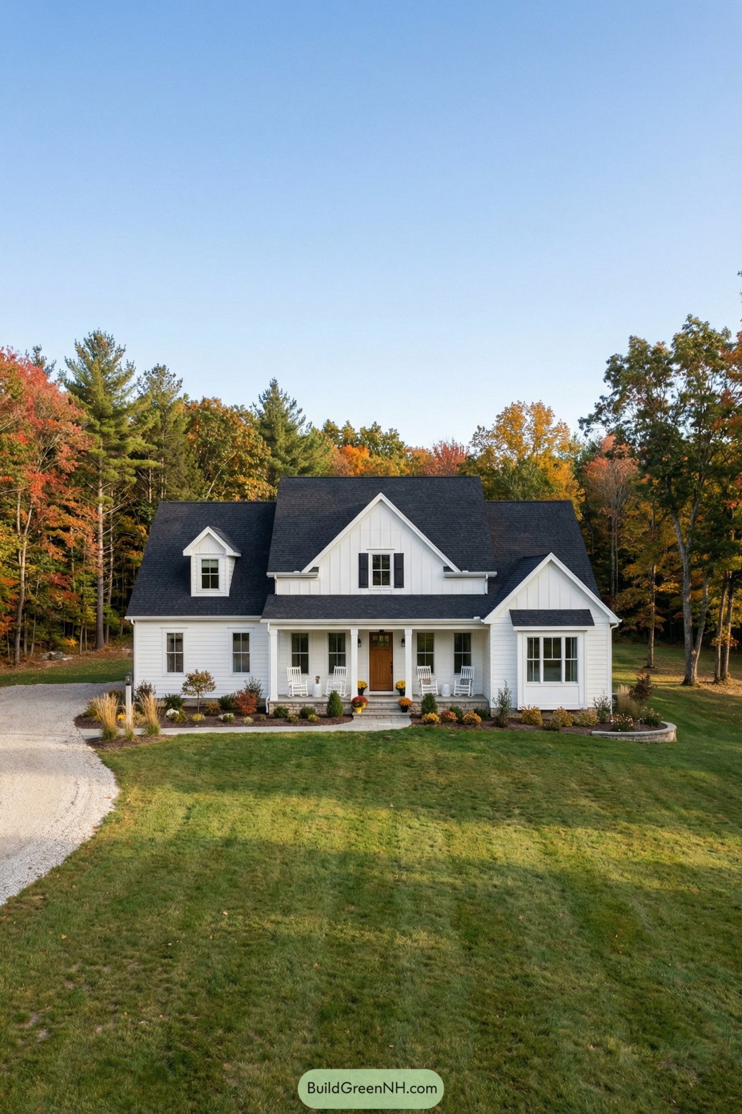 White farmhouse-style home with front porch, gabled roof, and wide lawn framed by fall trees