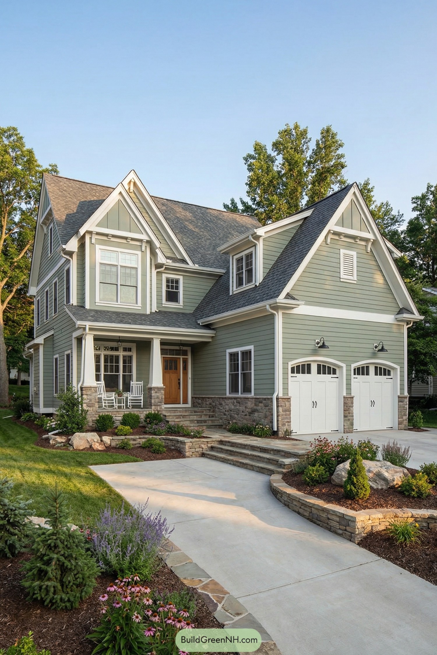 Two-story sage green house with white trim, stone base, and double garage