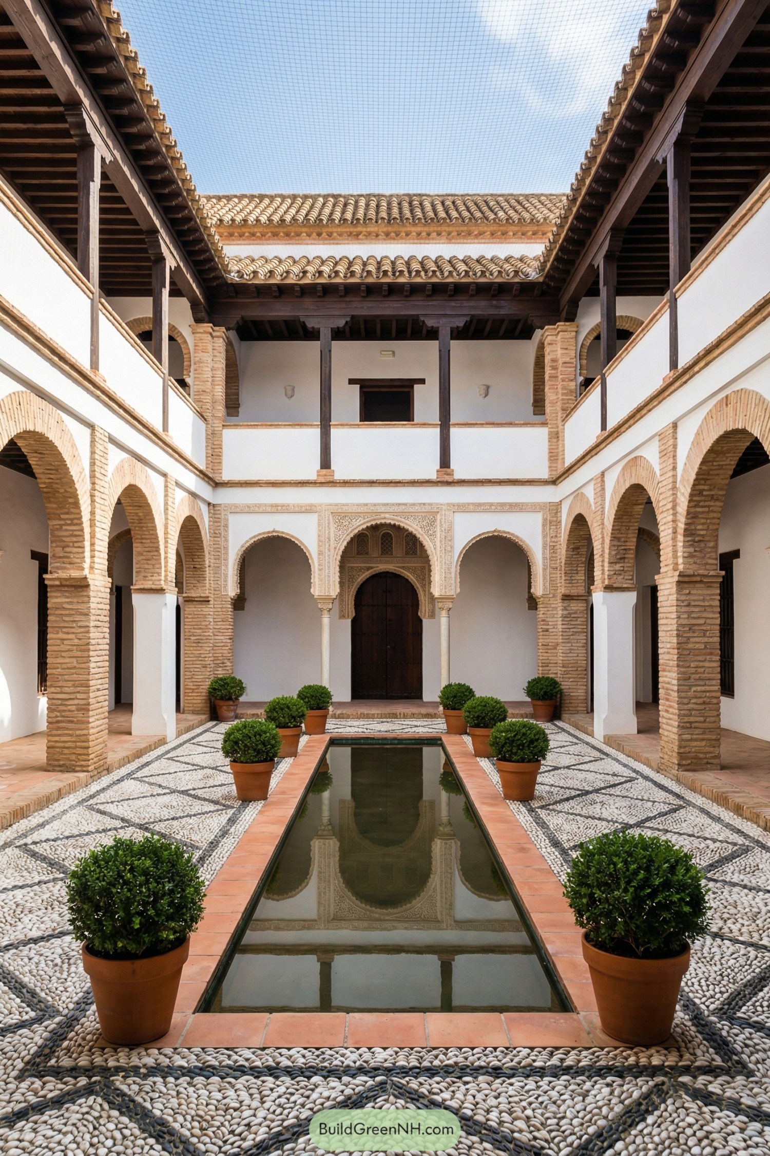 Traditional Spanish courtyard with central reflecting pool, pebble mosaic paving, and brick arcades on two levels