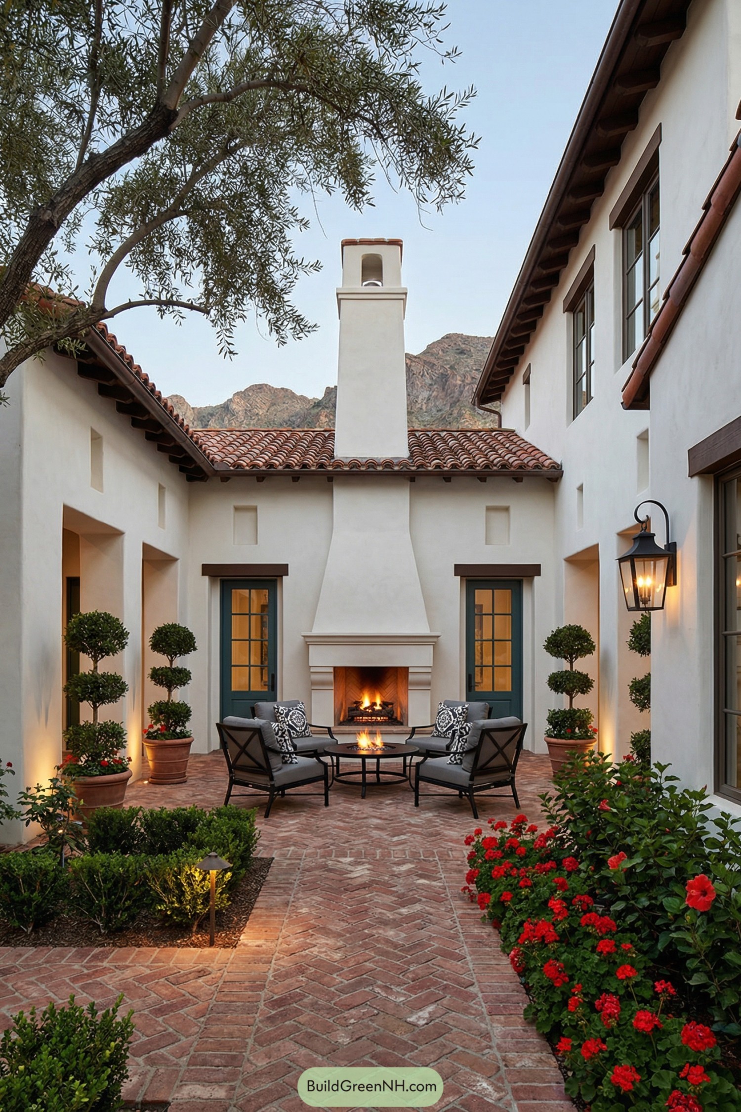 Intimate Spanish-style courtyard with brick herringbone paving, central outdoor fireplace, and surrounding greenery