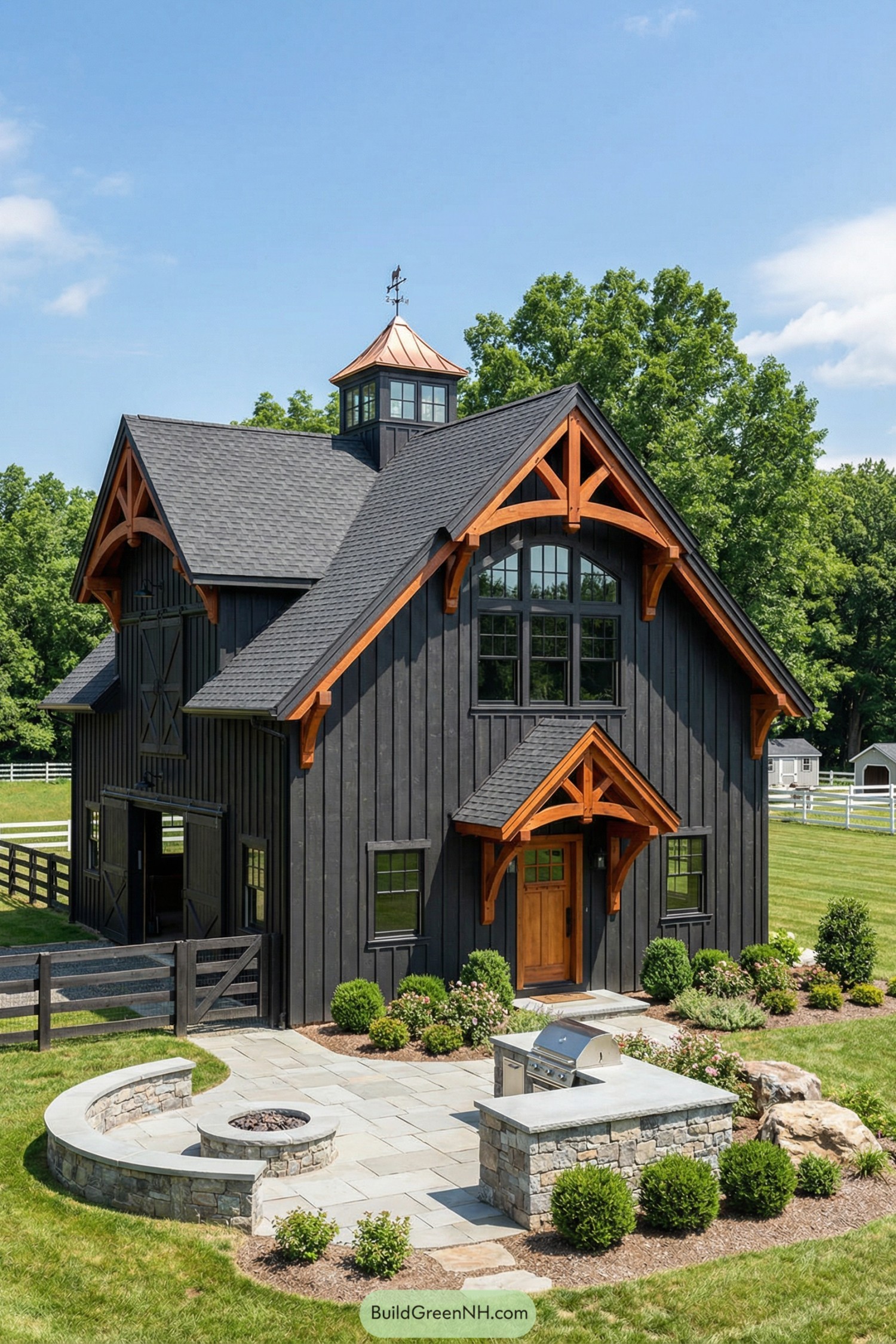 Black barn-style house with warm timber trusses cupola, and stone patio with fire pit and grill
