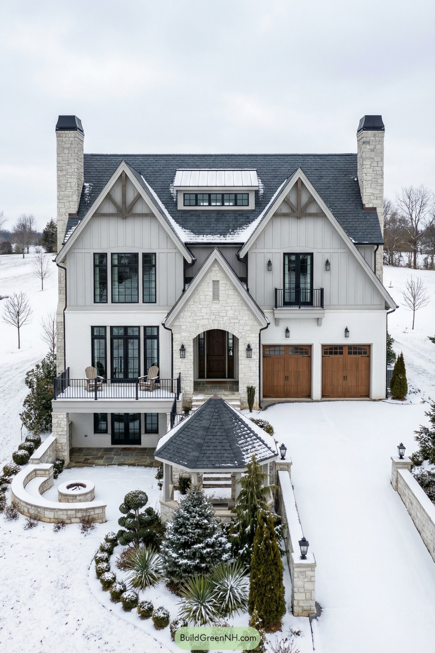 Snowy three story stone and siding manor with tall chimneys and front garden gazebo