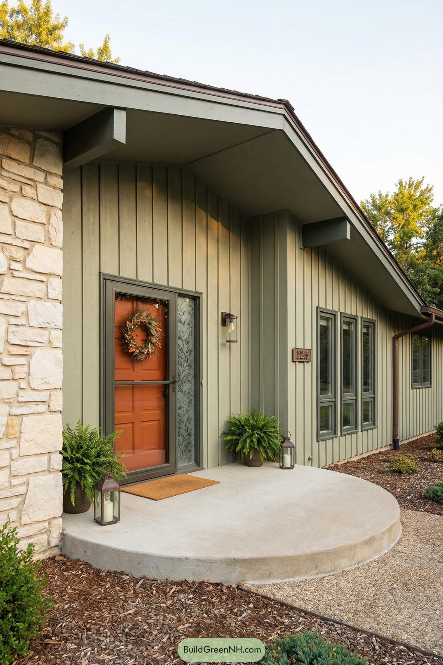 Green vertical siding ranch entry with orange door and round concrete porch