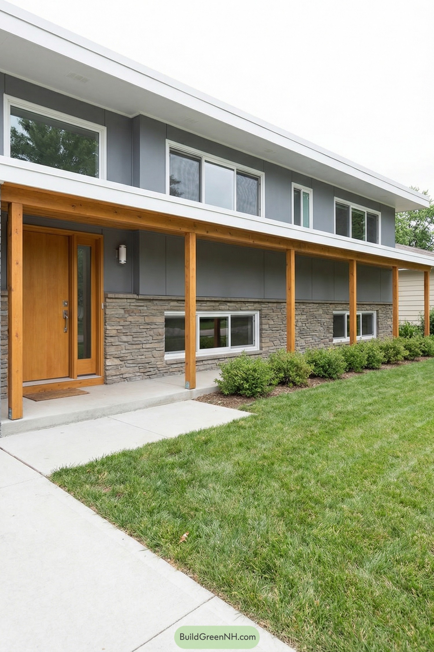 Modern split level home with gray siding stone base and warm wood porch posts
