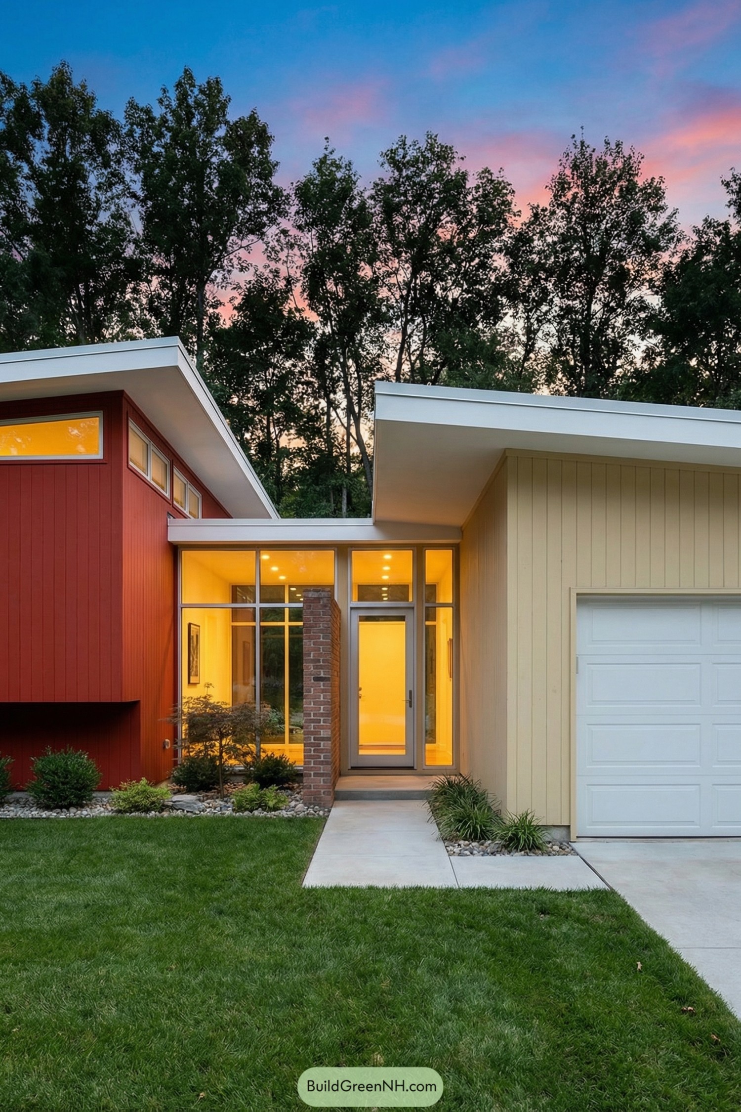 Midcentury style home with angled roofs and glassy entry glowing at dusk