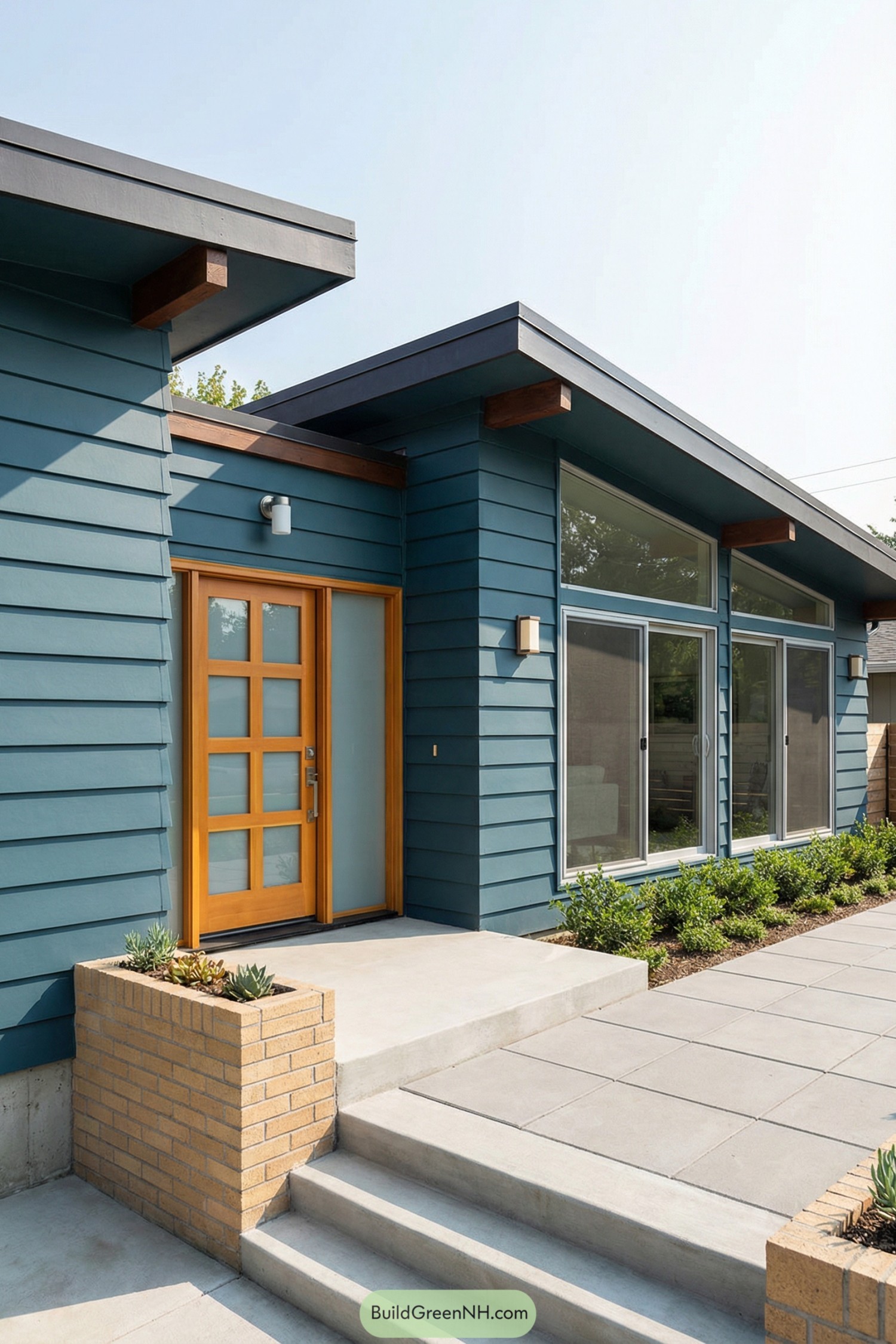 Midcentury style blue house with bright wood front door and large modern windows