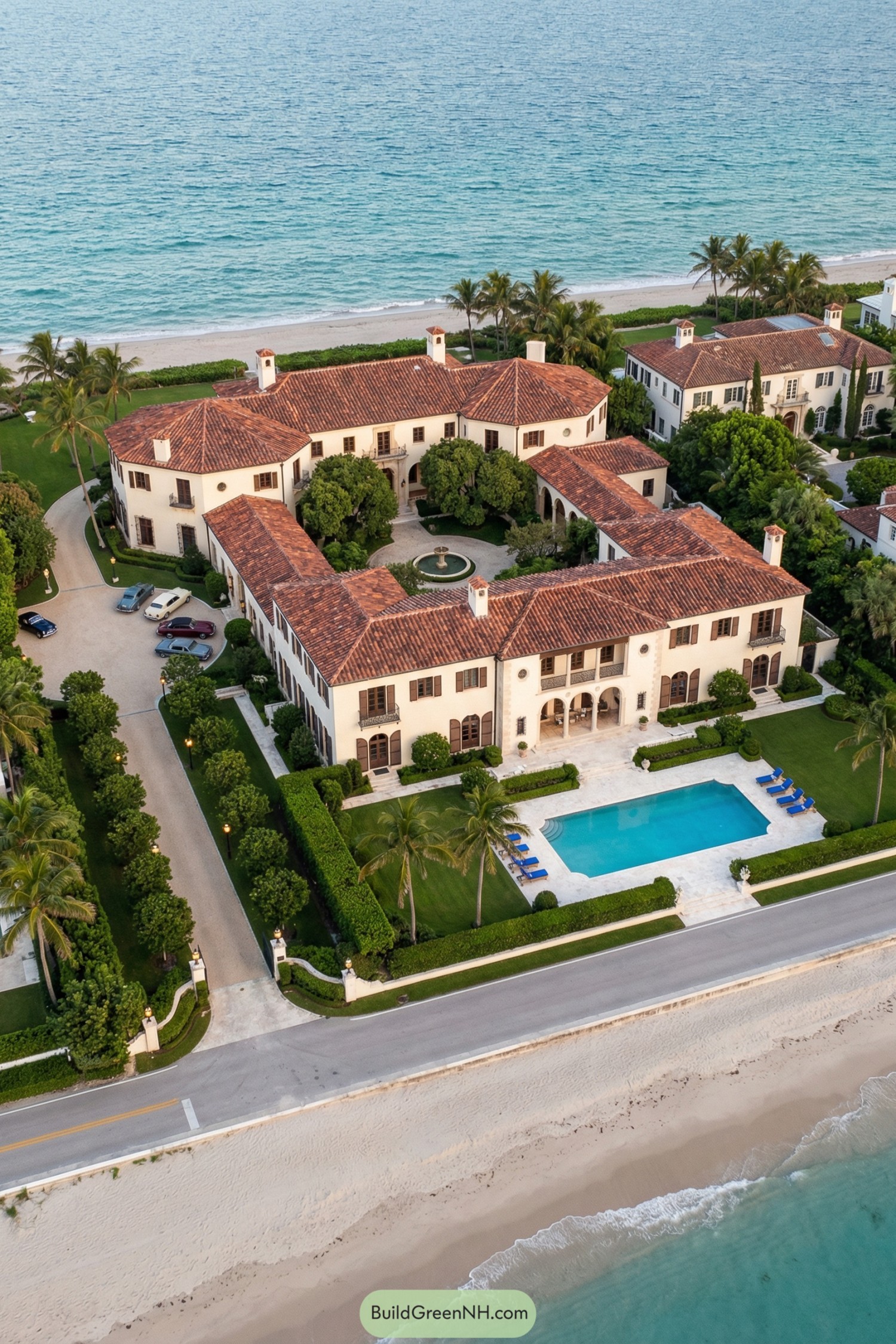 Mediterranean style beachfront mansion with red tile roofs, central courtyard fountain, and oceanfront pool