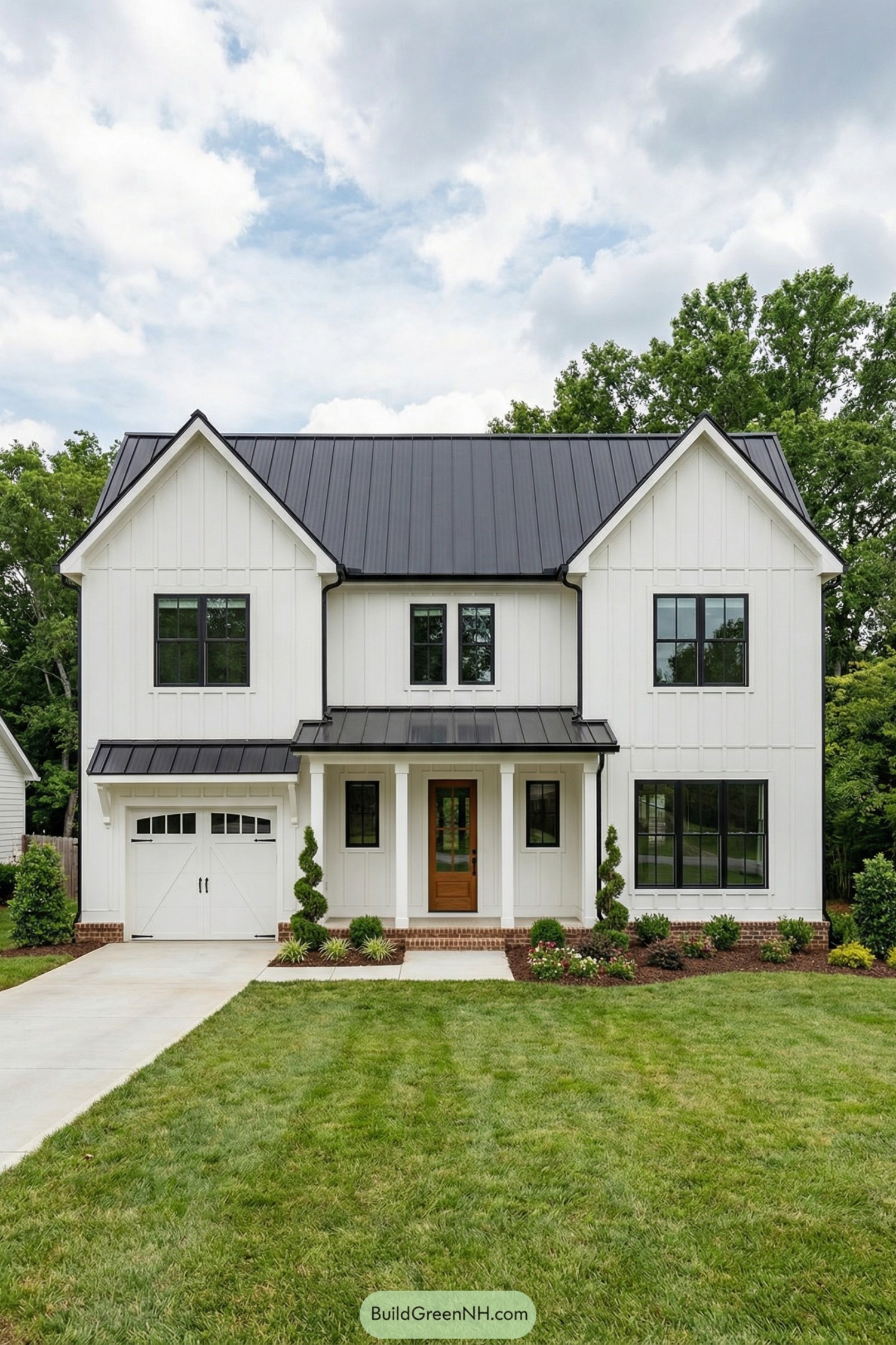 Two story white modern farmhouse with black metal roof and front porch