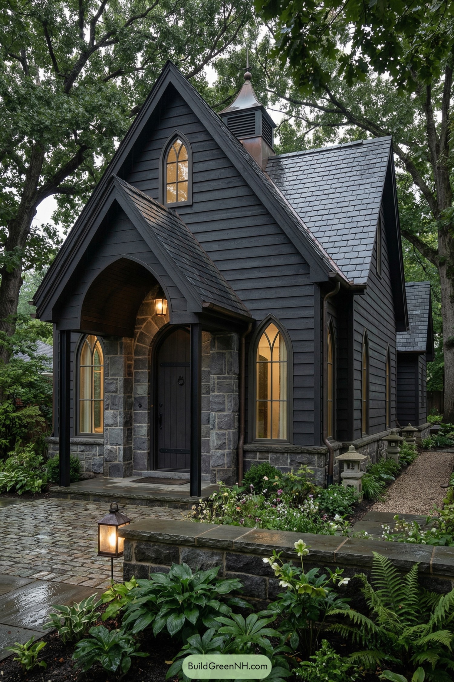 Dark charcoal cottage with stone base, pointed arches, and lush garden path at dusk