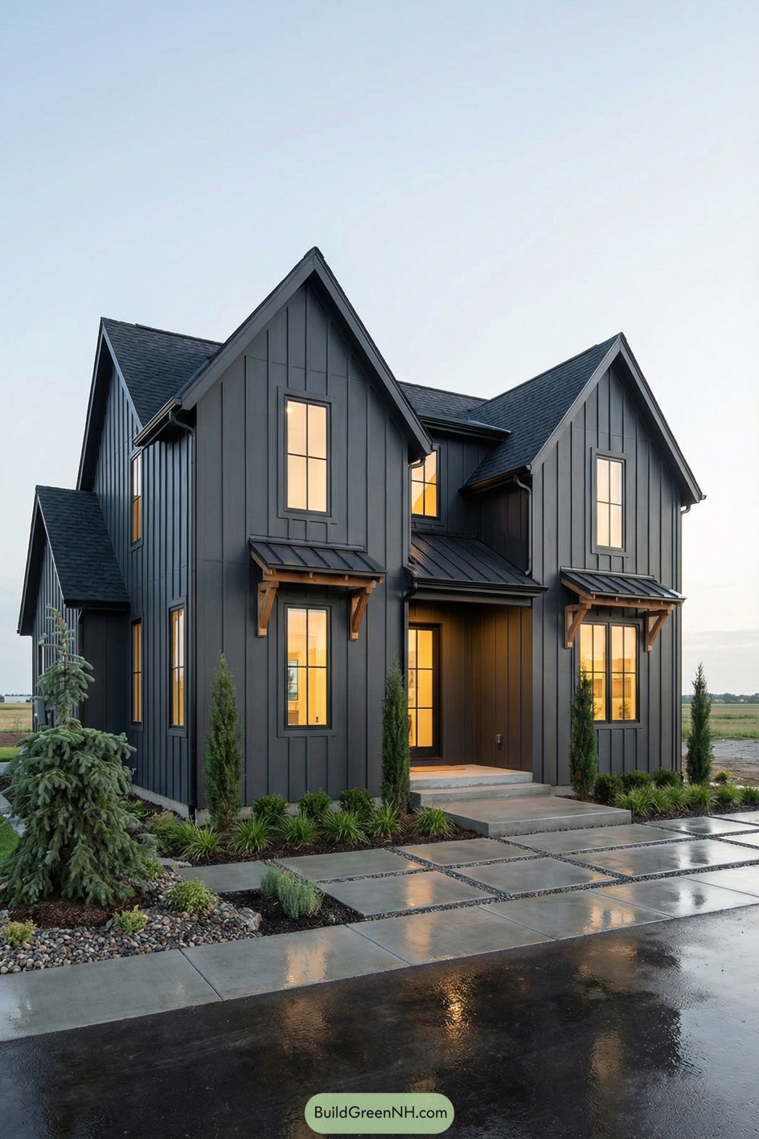 Modern dark board and batten cottage with warm interior glow and simple landscaping