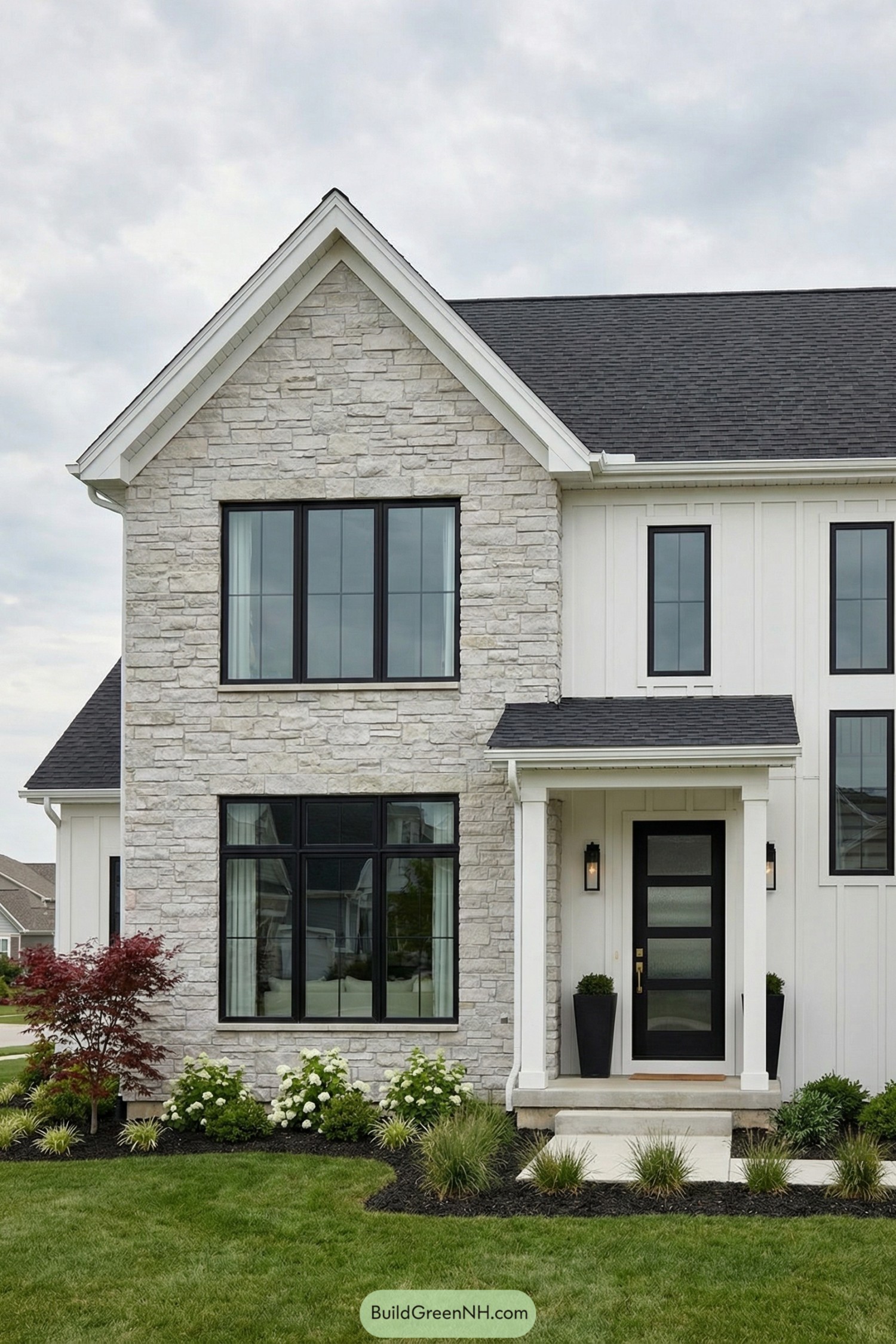 Modern white house exterior with large black-framed front windows and stone facade