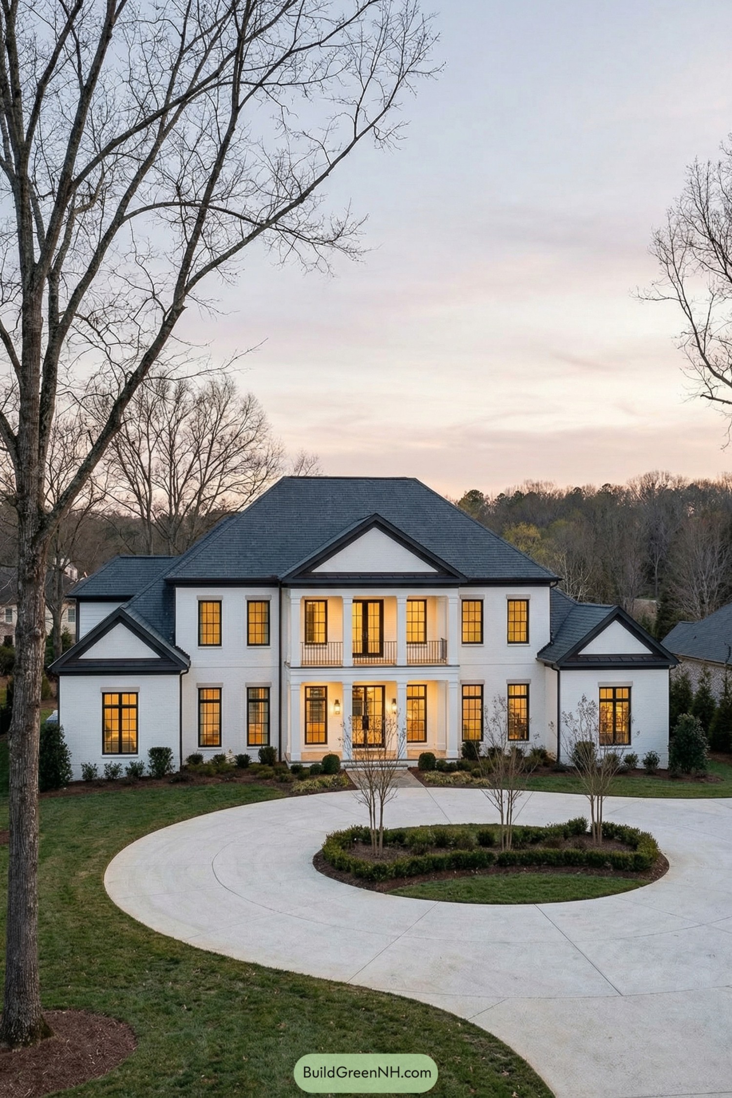 Large white brick two story house with circular driveway at dusk