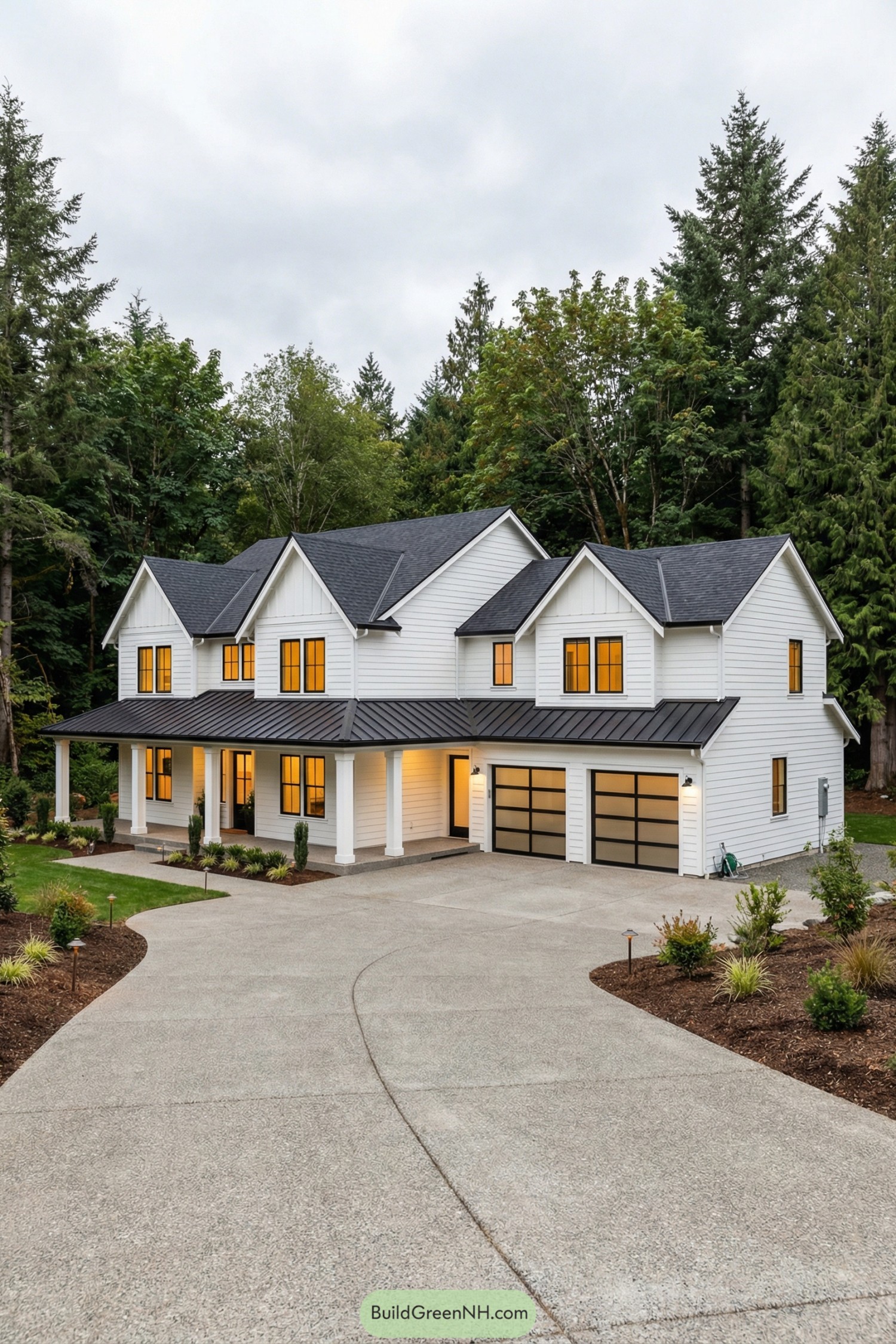 Modern white farmhouse with black roof and large front porch set against tall evergreen trees