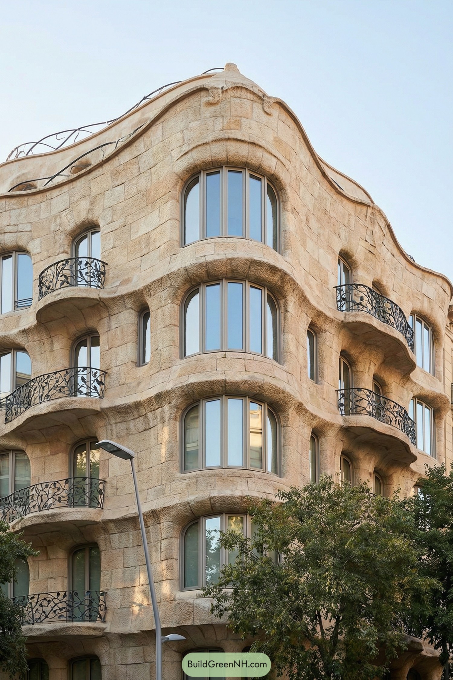 Curving stone apartment facade with wavy balconies and arched windows